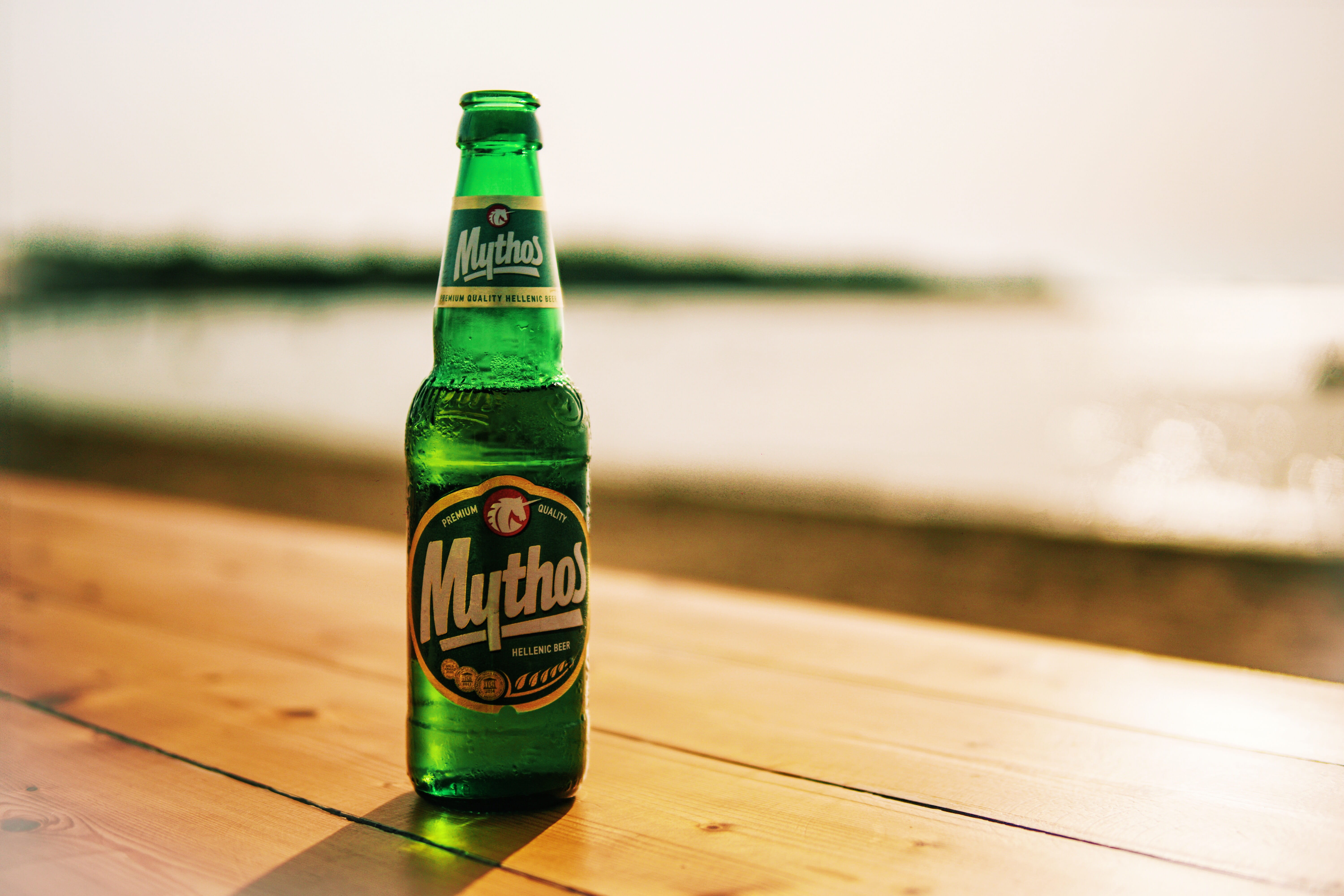 bottle, labeled, indoors, water, close-up, blur, drink, sea, ad, no people, 5K, method, wood - material, refreshment, near, table, alcohol, beer - alcohol, HD Wallpaper