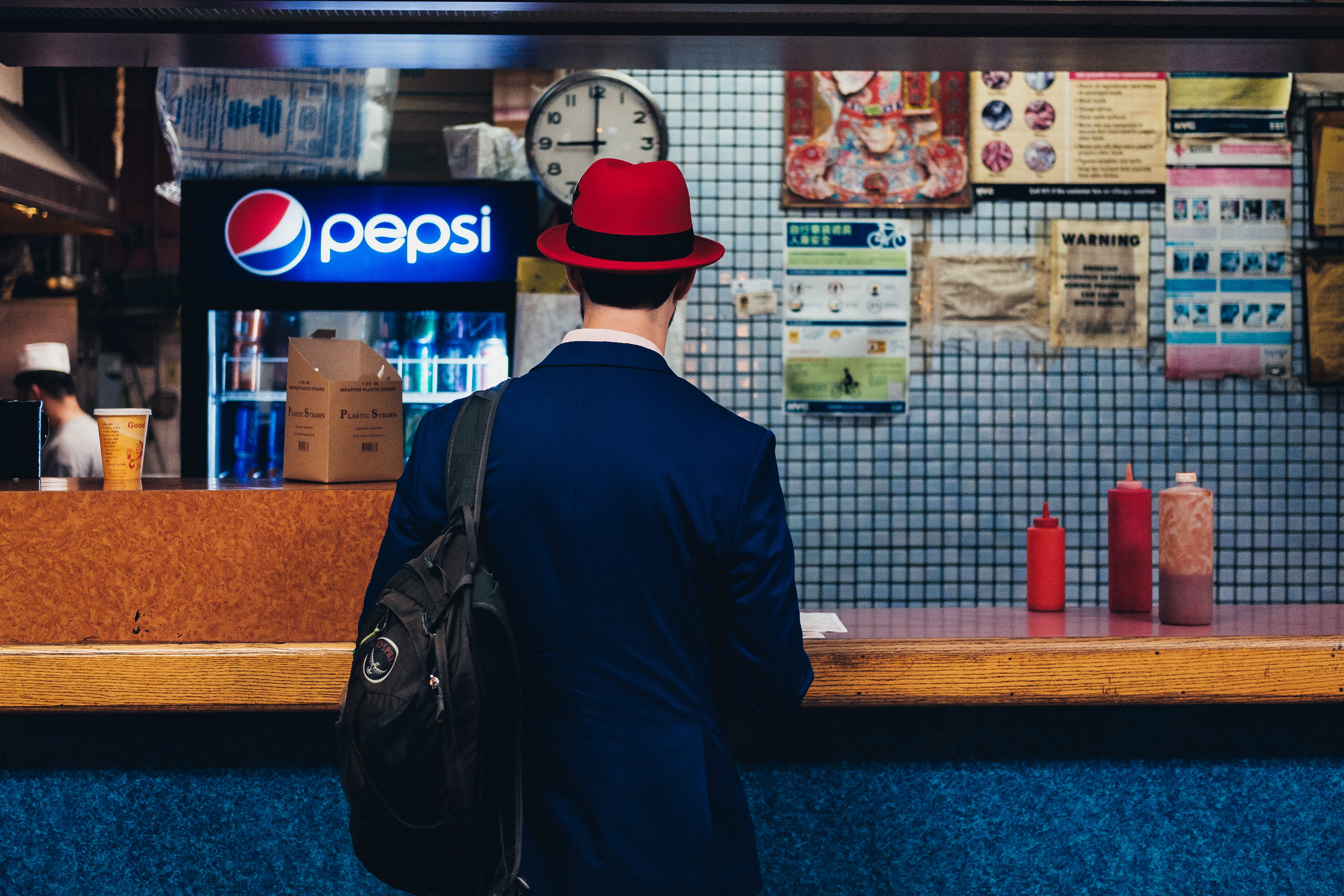 nyc, men, new york, 2K, technology, bar side, city, red hat, travel, candid, ordering, backpack, take, male, business, indoors, primary color, editorial, HD Wallpaper