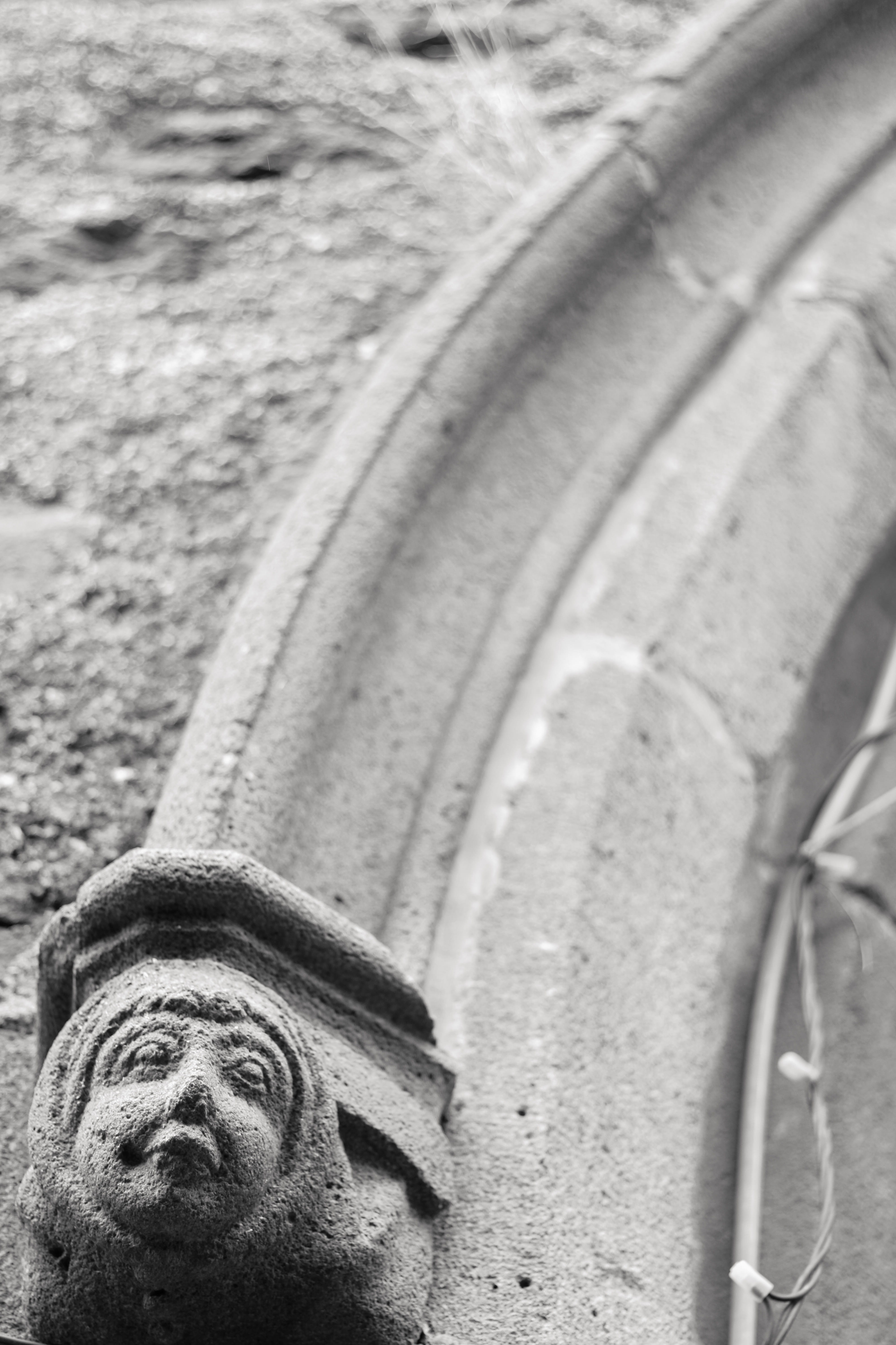 stone, 5K, selective focus, history, male likeness, saint flour, low angle view, face, black and white, built structure, architecture, frontporch of a church in saint flour, Phone HD Wallpaper