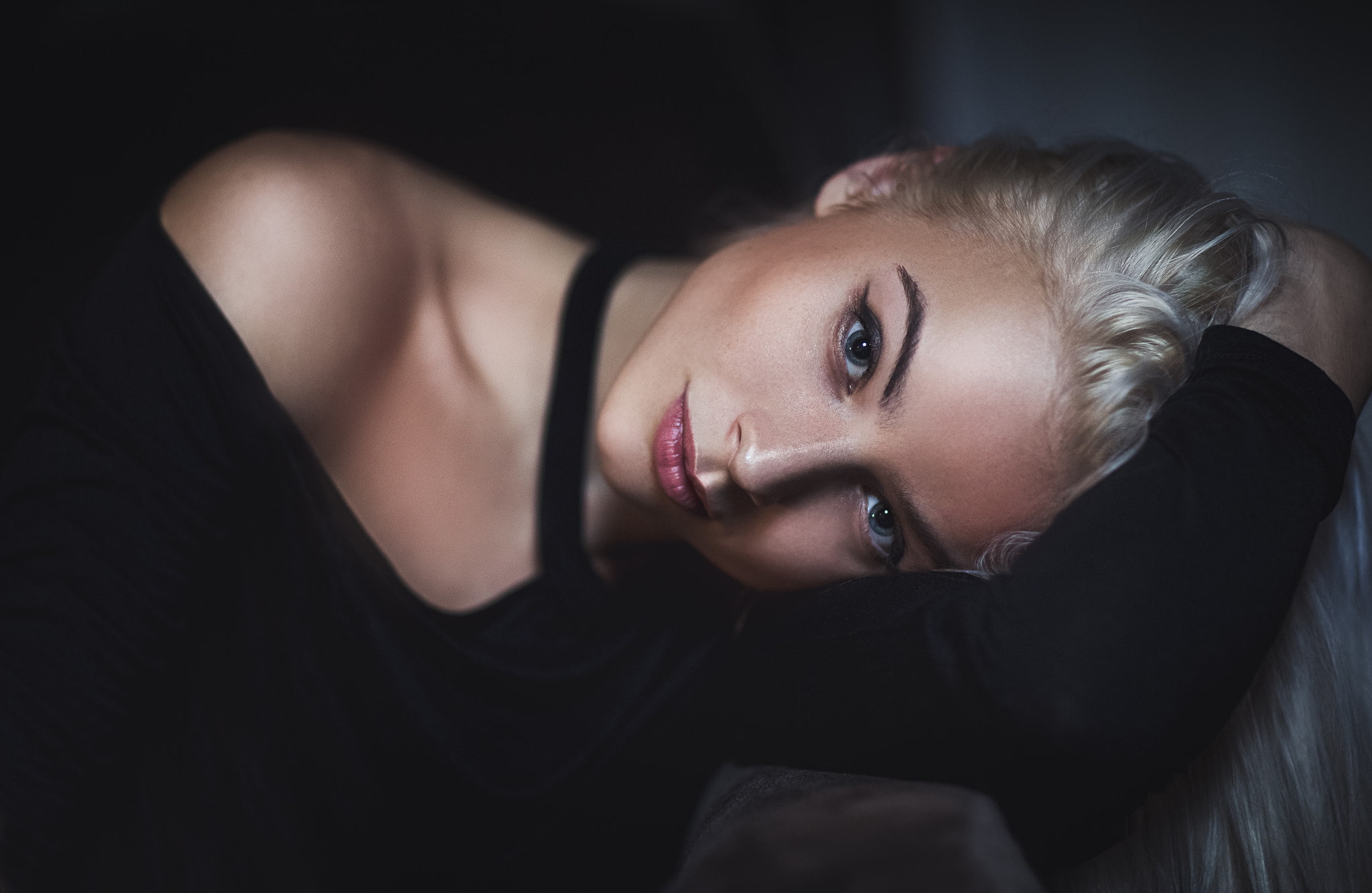 hair, bed, dark, blue eyes, face, black background, looking at camera, hairstyle, waist up, blonde, adult, 1080P, indoors, beauty, lying down, tanned, HD Wallpaper