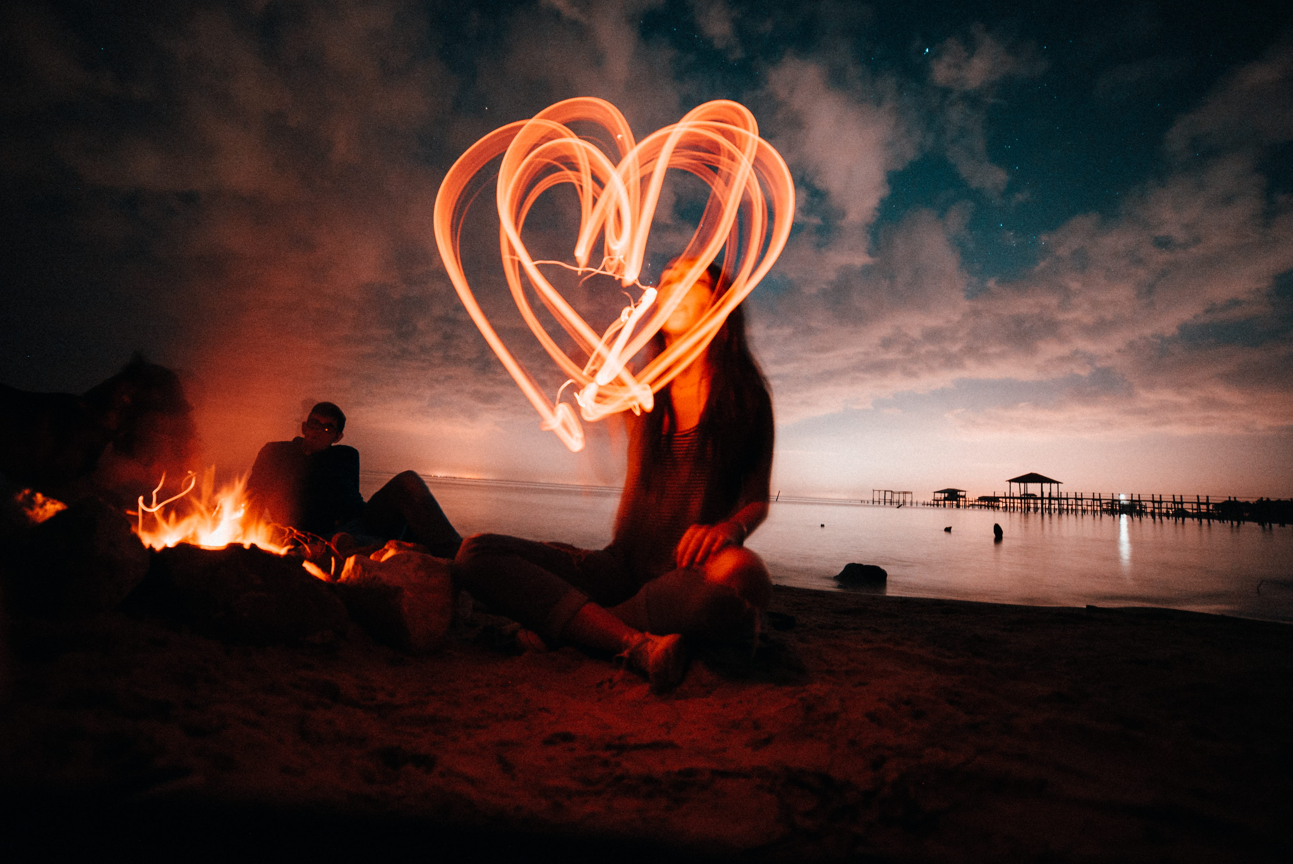 fire - natural phenomenon, sitting, full length, beach life, illuminated, ocean, heart shape, silhouette, people, low shutter speed, night time, nature, HD Wallpaper