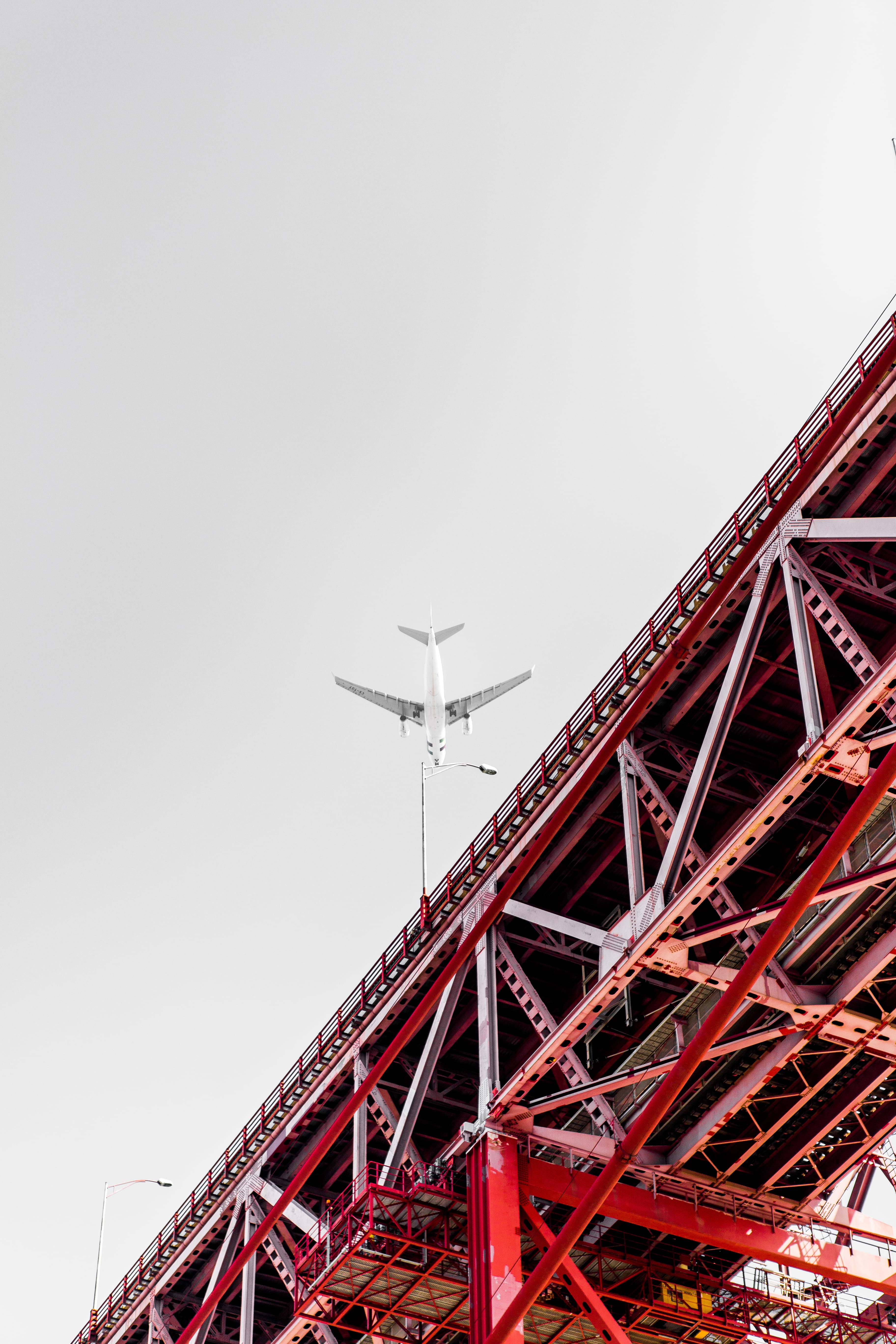 plane, flying, metal, architecture, white, mode of transportation, flyover, low, picture, red, airplane, angle, day, famous Place, outdoors, bridge, 5K, Phone HD Wallpaper