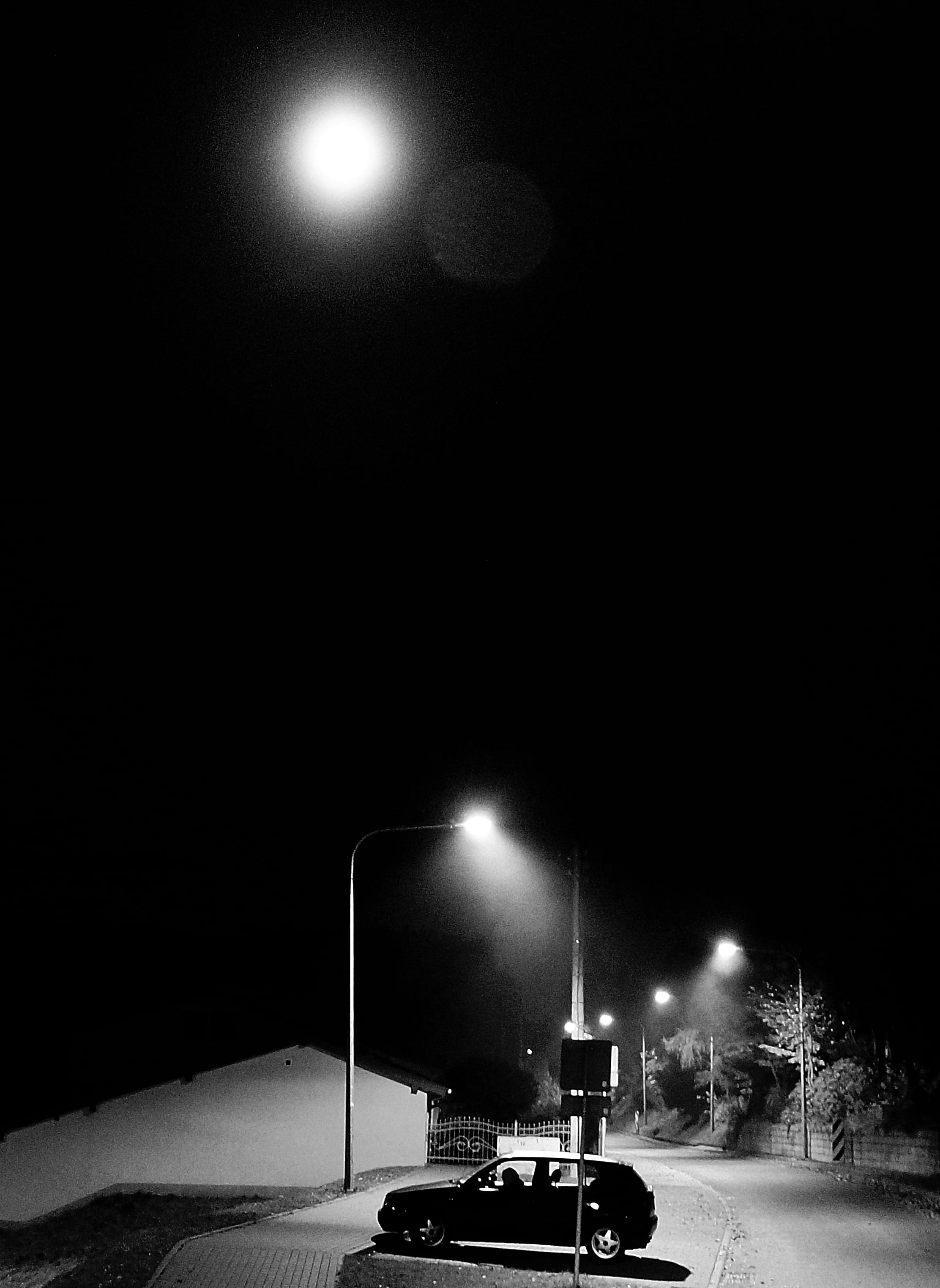 2K, night, monochrome, darkness, city, door, road, streetlights, hatchback, nature, land vehicle, dark, street light, light, mode of transportation, no people, Phone HD Wallpaper