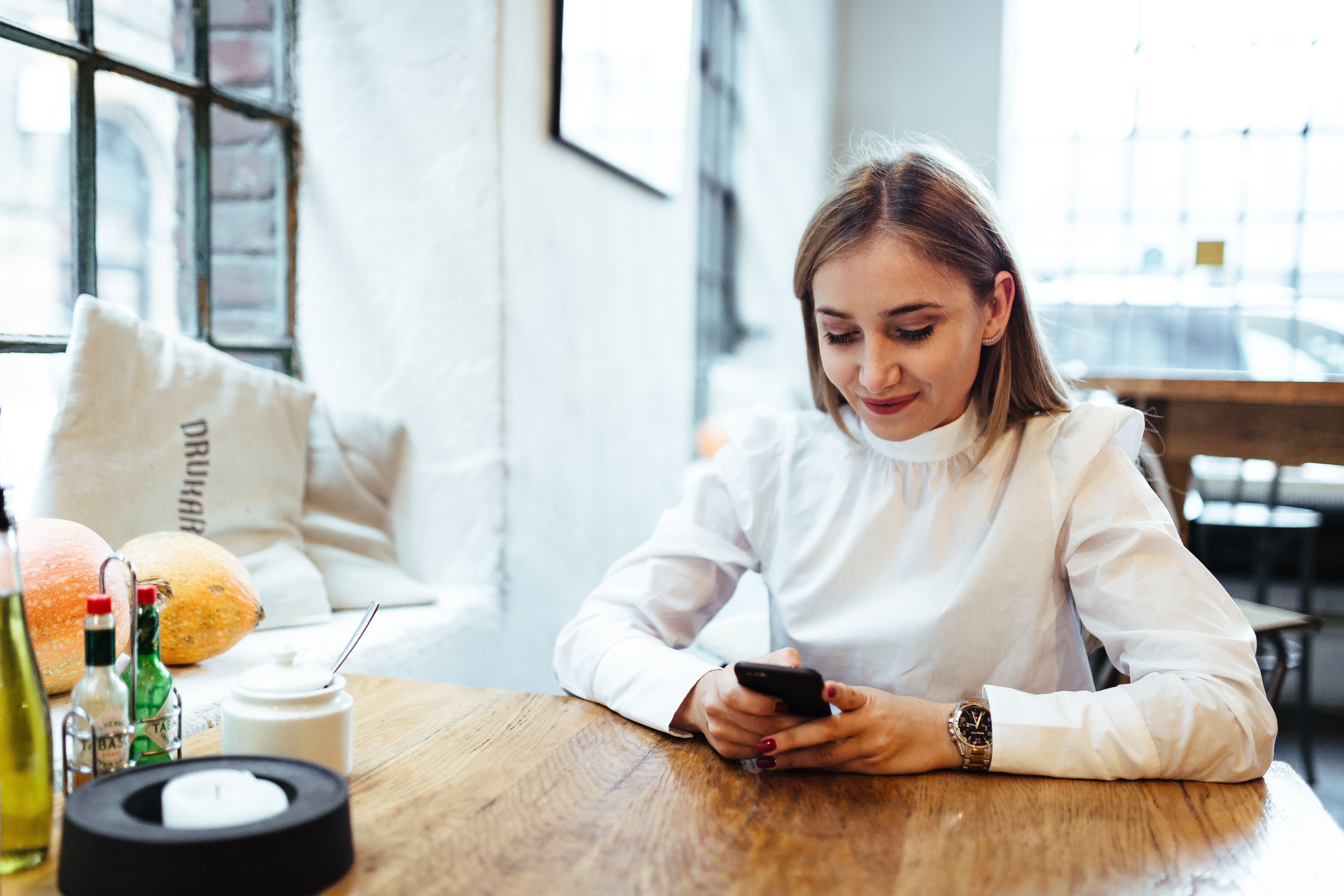 indoors, lifestyles, working, looking down, drink, table, food and drink, mobile phone, adult, smiling, cafe, wristwatch, sitting, connection, only Women, HD Wallpaper