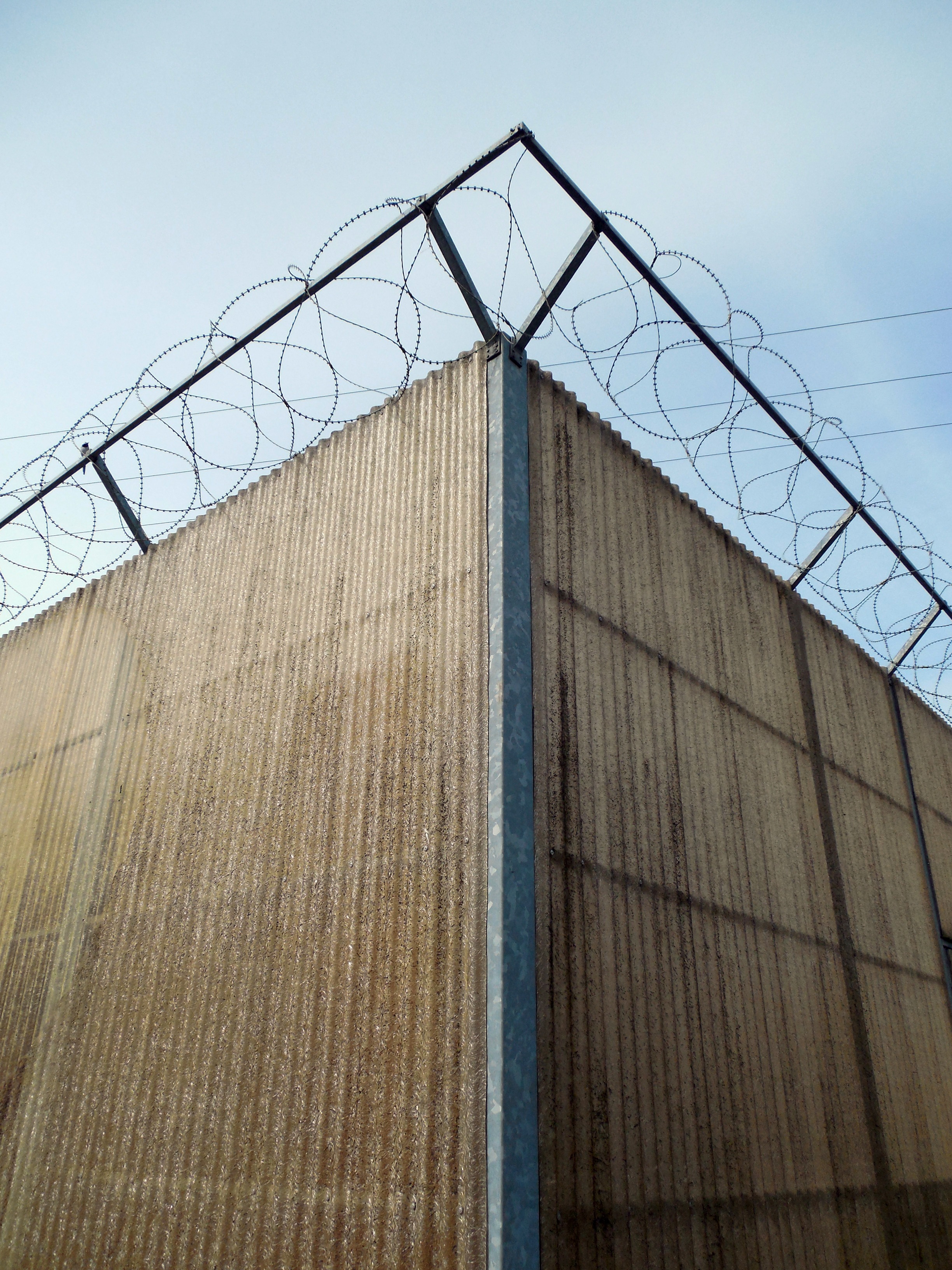 building exterior, safety, no people, fence, building, wall - building feature, architecture, boundary, 2K, sure, steel, security, imprisoned, barbed wire fence, Phone HD Wallpaper