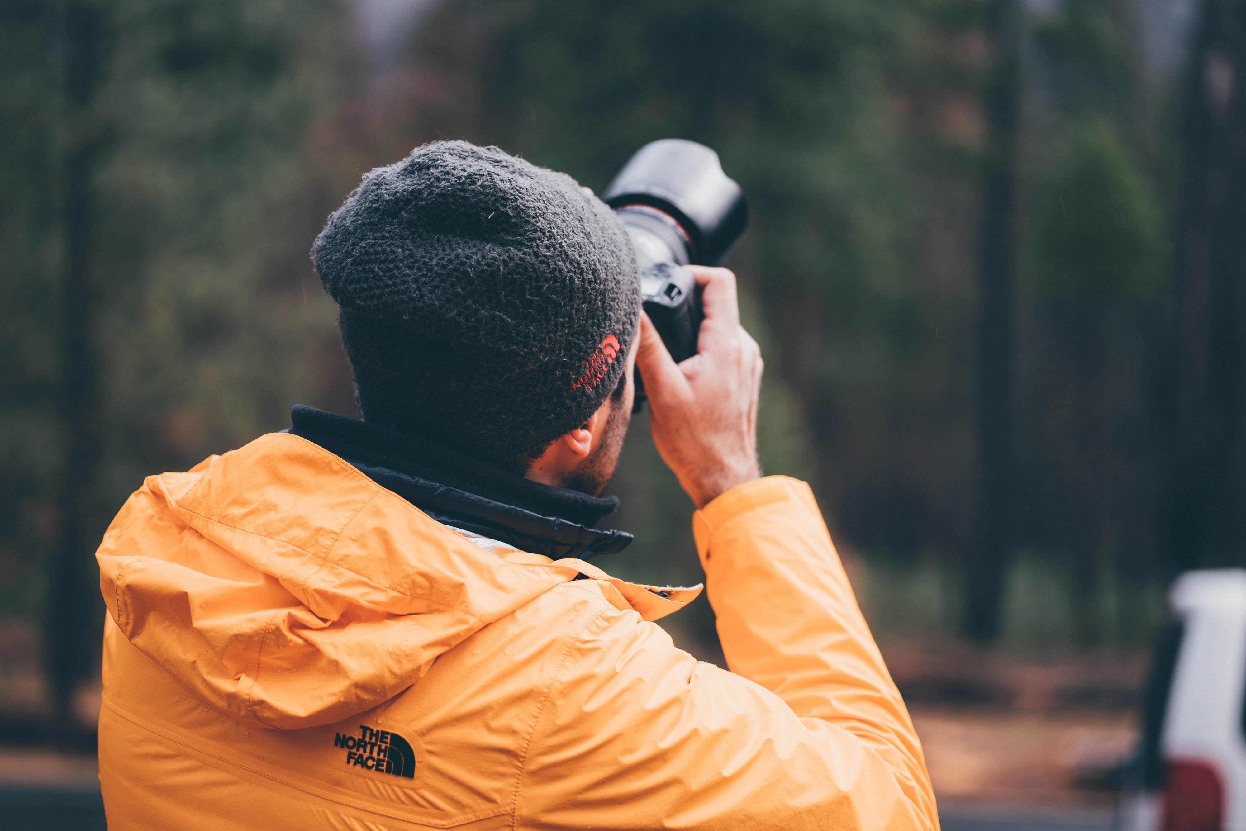 photo, backwards, 4K, holding, camera, technology, black, hat, coat, activity, outdoors, dslr, standing, male, leisure activity, winter, rear view, yellow, HD Wallpaper