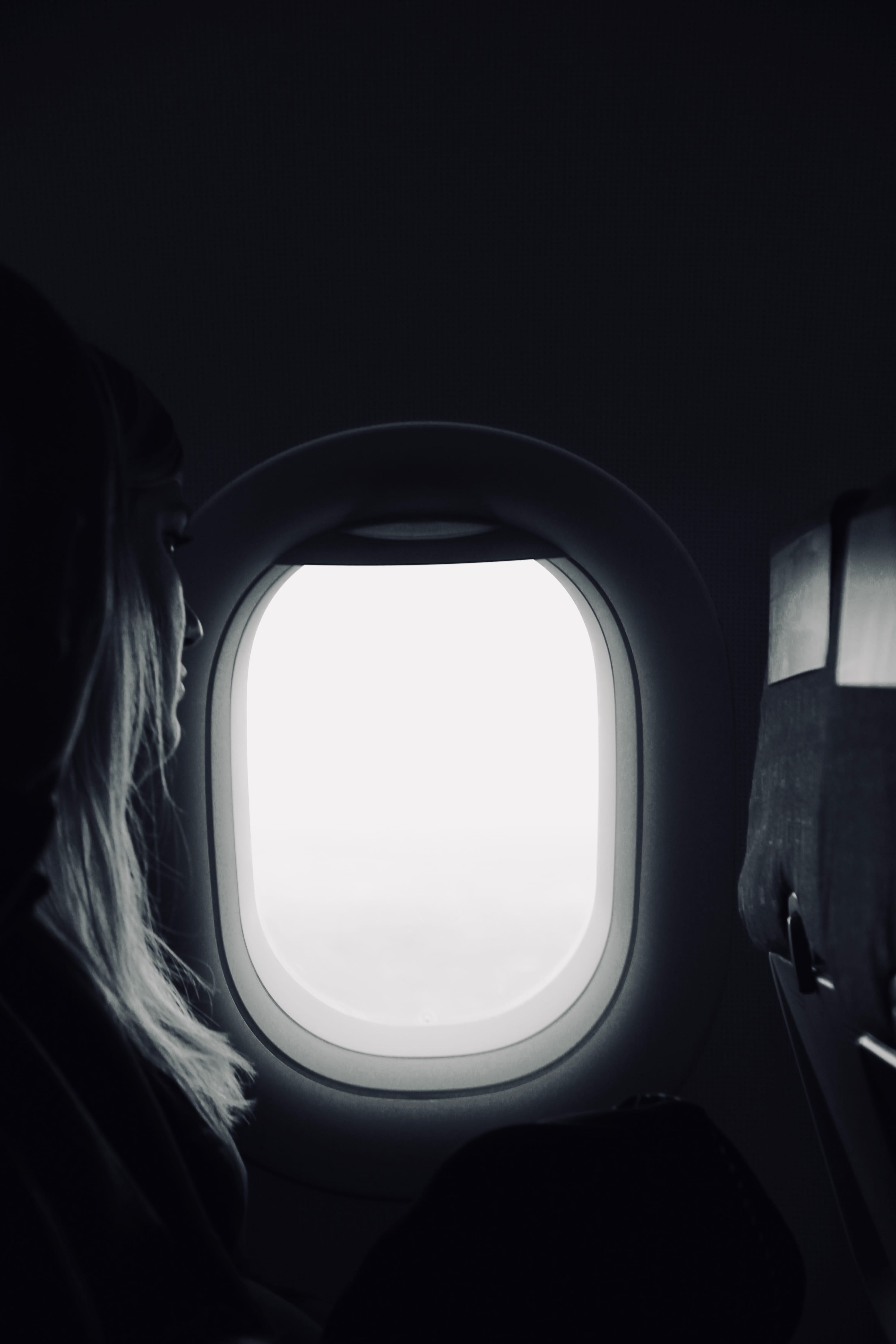 4K, sitting, public transportation, vehicle interior, flying, day, nature, looking out the window, window seat, plane window, woman, tarveling, air, black and white, Phone HD Wallpaper