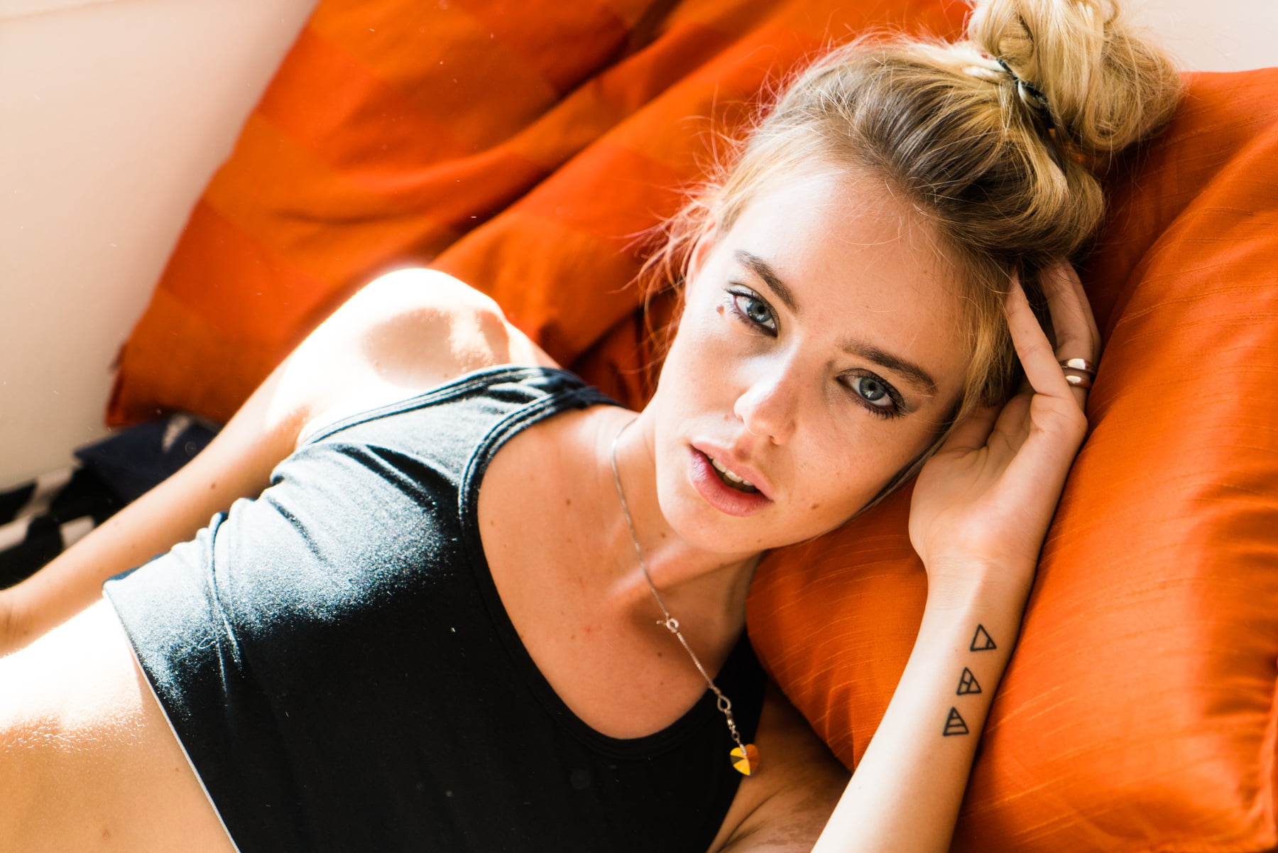 blond hair, 720P, women indoors, looking at viewer, tank top, women, laying on side, black clothing, HD Wallpaper