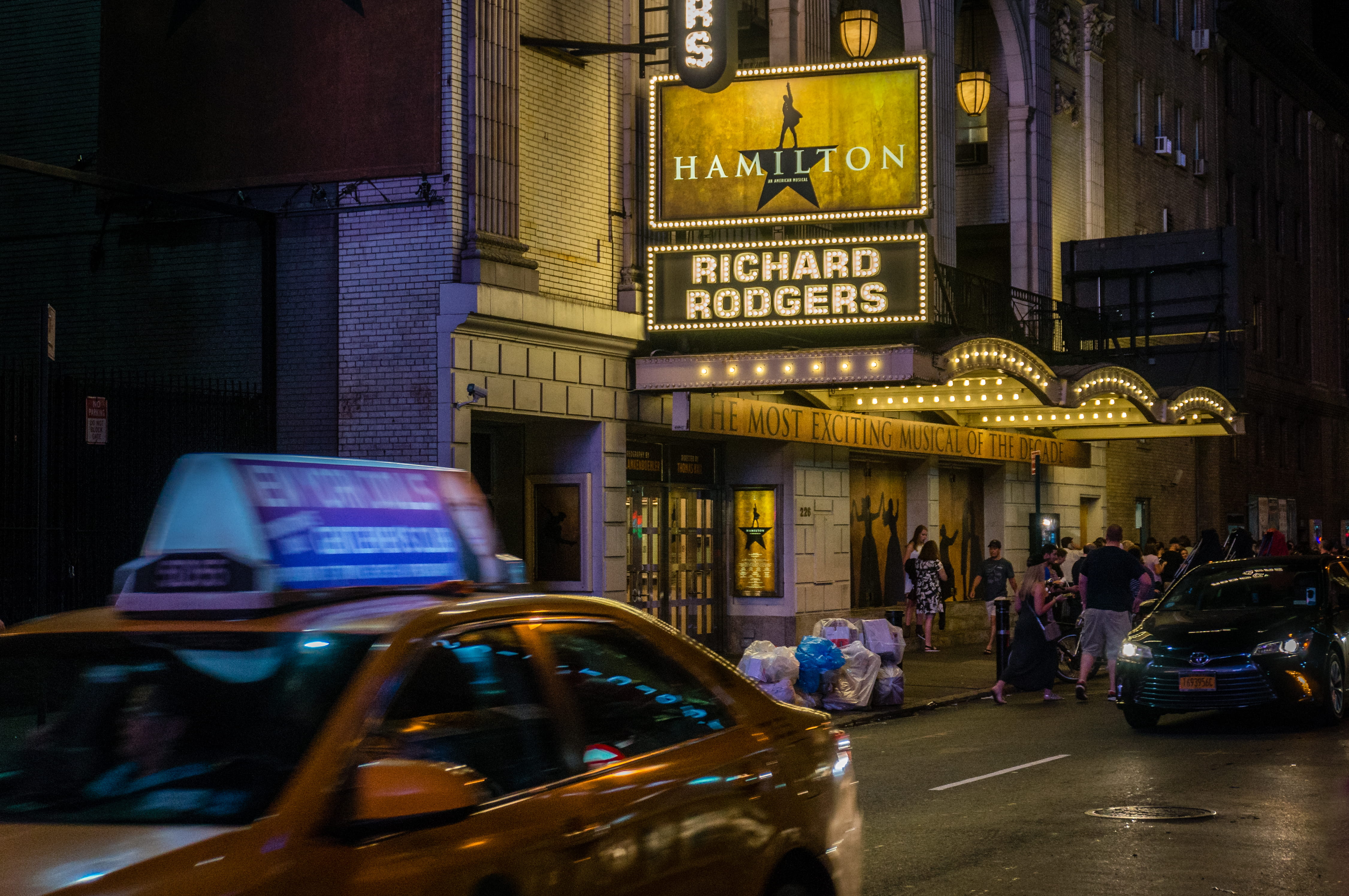 incidental people, night, sign, poster, broadway, building exterior, land vehicle, advertisement, text, road, taxi, city life, street, city street, trash, HD Wallpaper