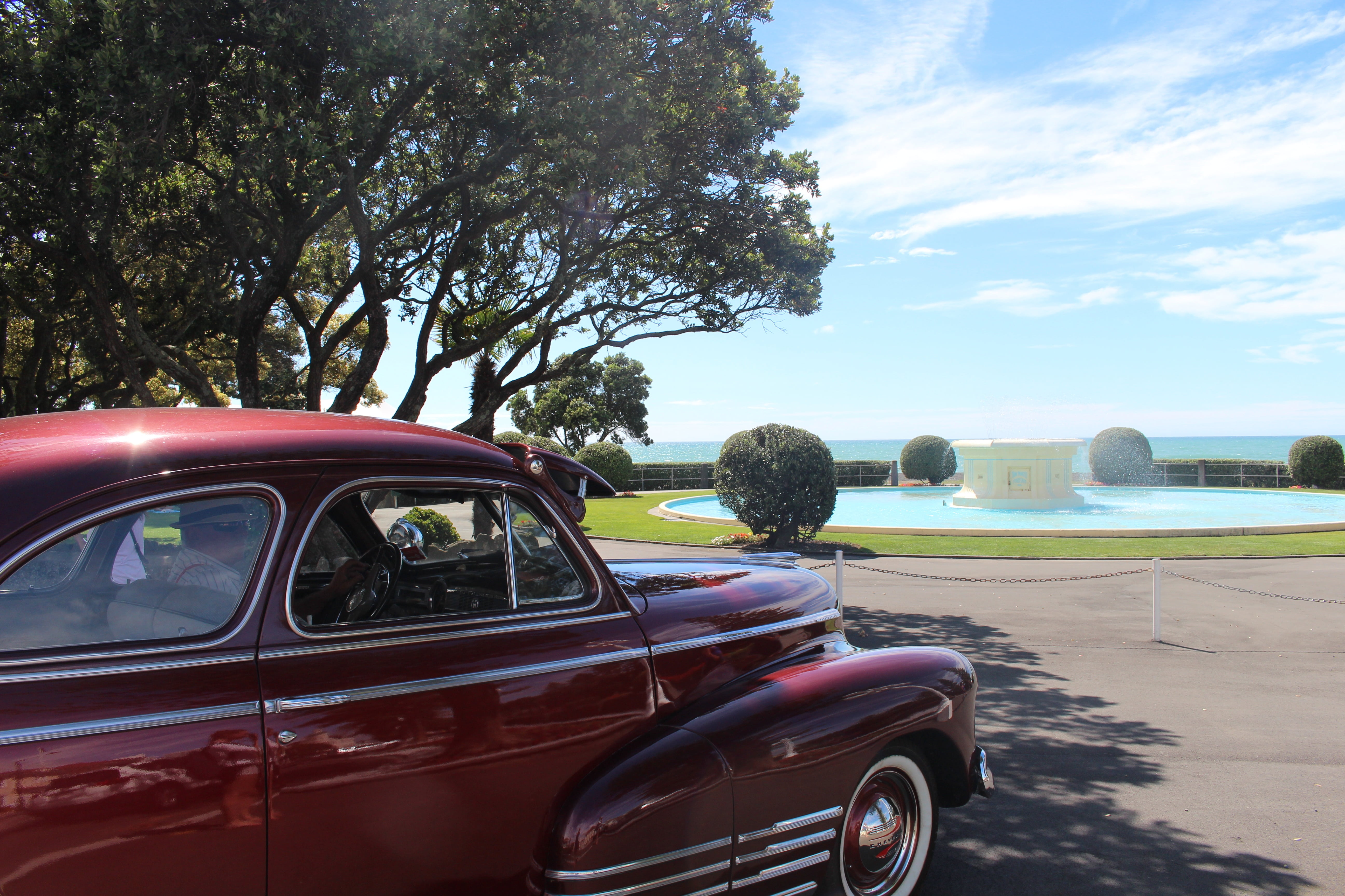 fountain, wheel, new zealand, daytime, sea, napier, architecture, auto, 5K, luxury, vehicle, sky, trees, sun, landscape, cloud - sky, red car, tree, land vehicle, HD Wallpaper