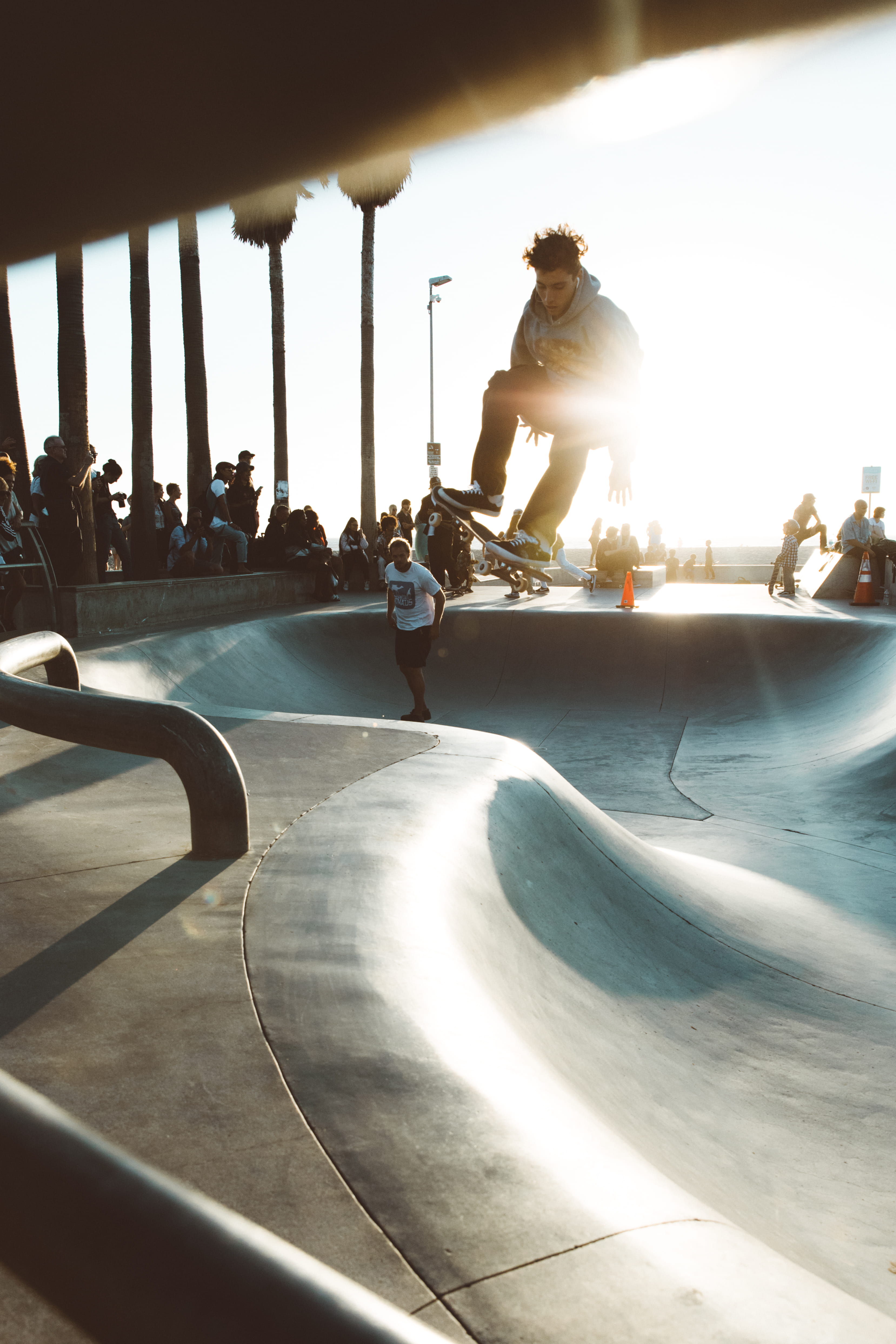 jump, outdoors, lens flare, playing, lifestyles, jumper, sport, skill, crowd, real people, balance, people, skate board, skateboard, skating, sunray, leisure activity, Phone HD Wallpaper