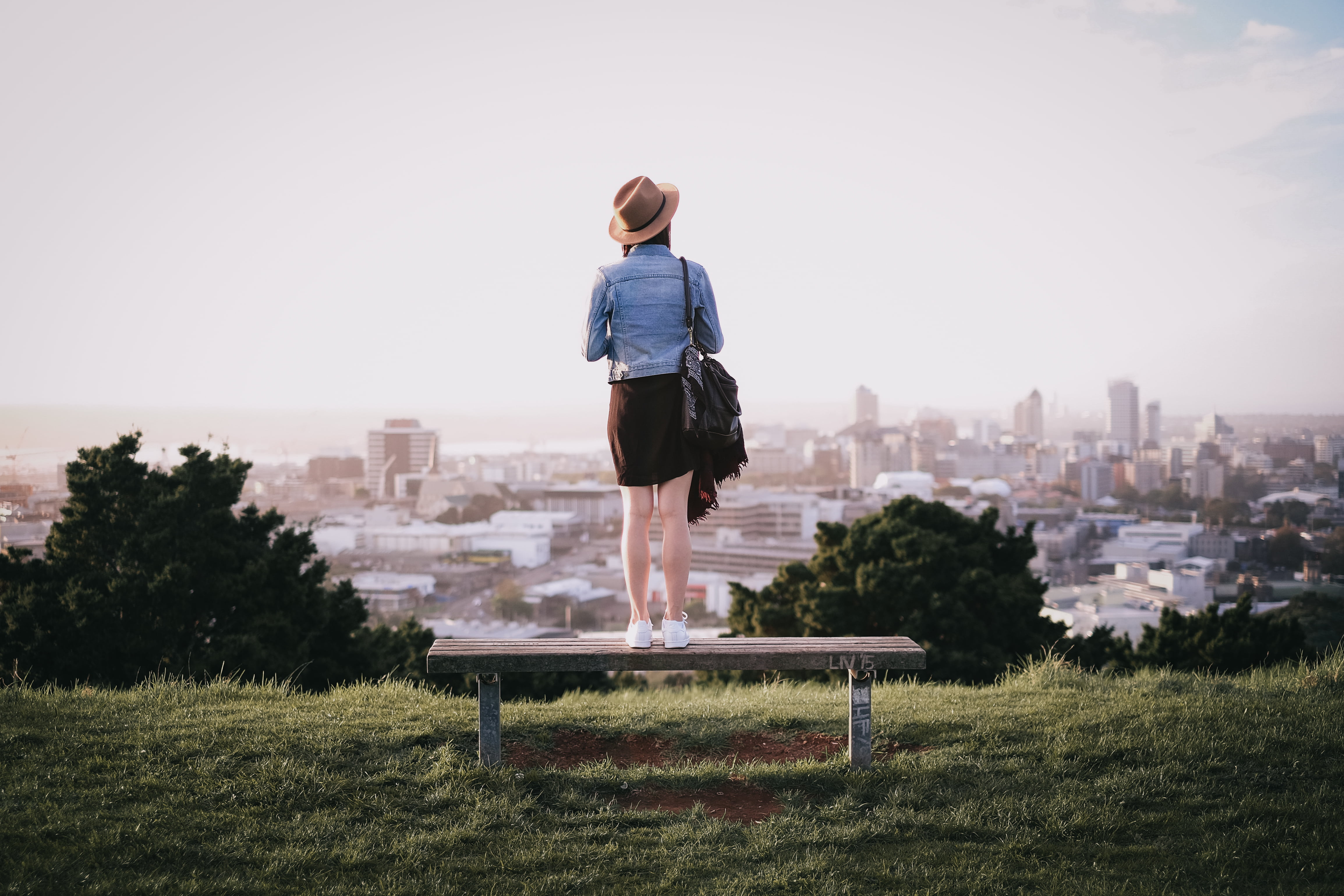 outdoors, cityscape, real people, people, shorts, brown, building, skyscraper, infrastructure, city, trees, wooden, bench, leisure activity, highland, grass, HD Wallpaper