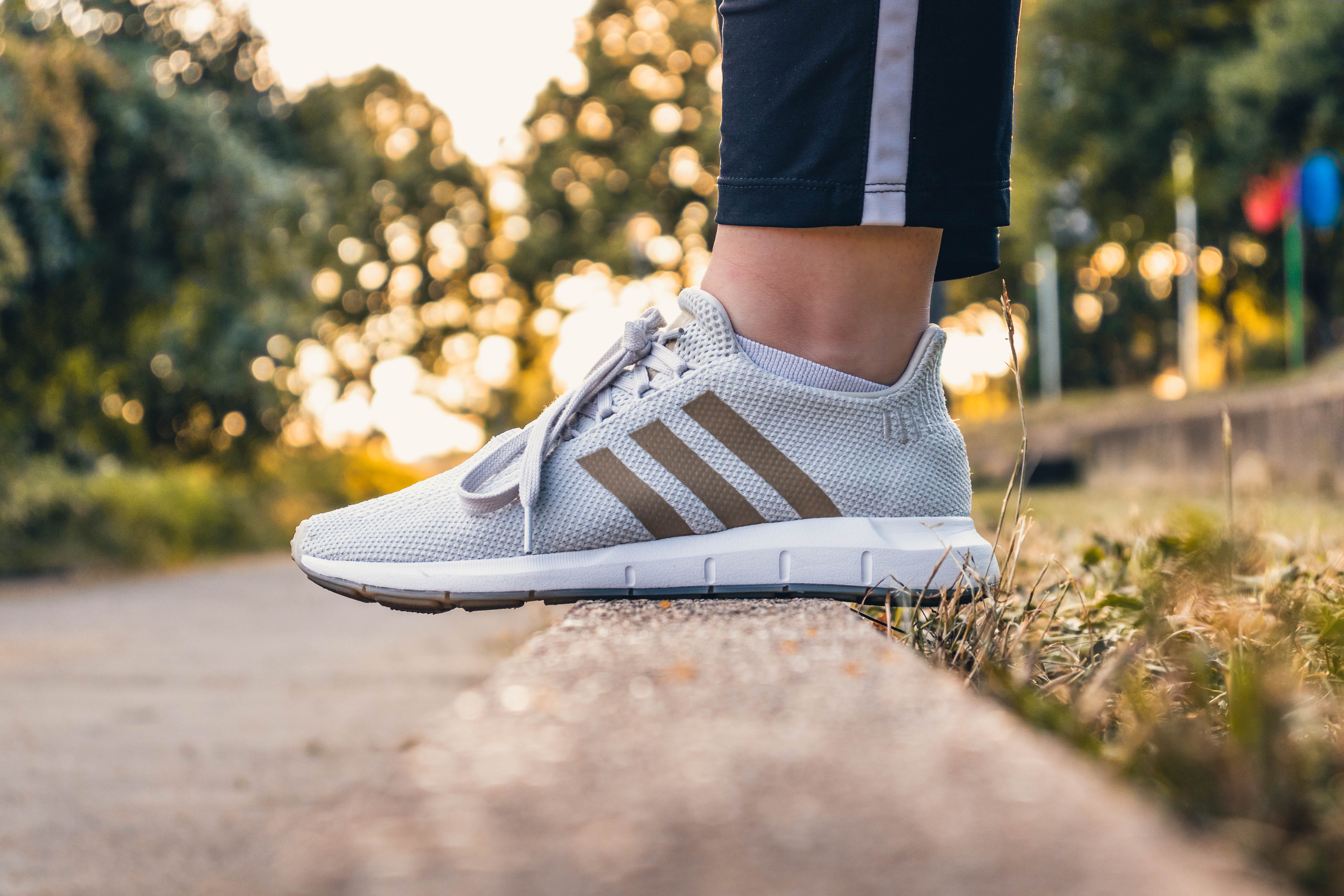 adidas, plant, selective focus, lifestyles, sneaker, standing, shoe, sunset, 5K, outdoors, swift, swift run, one person, human limb, sunlight, real people, HD Wallpaper
