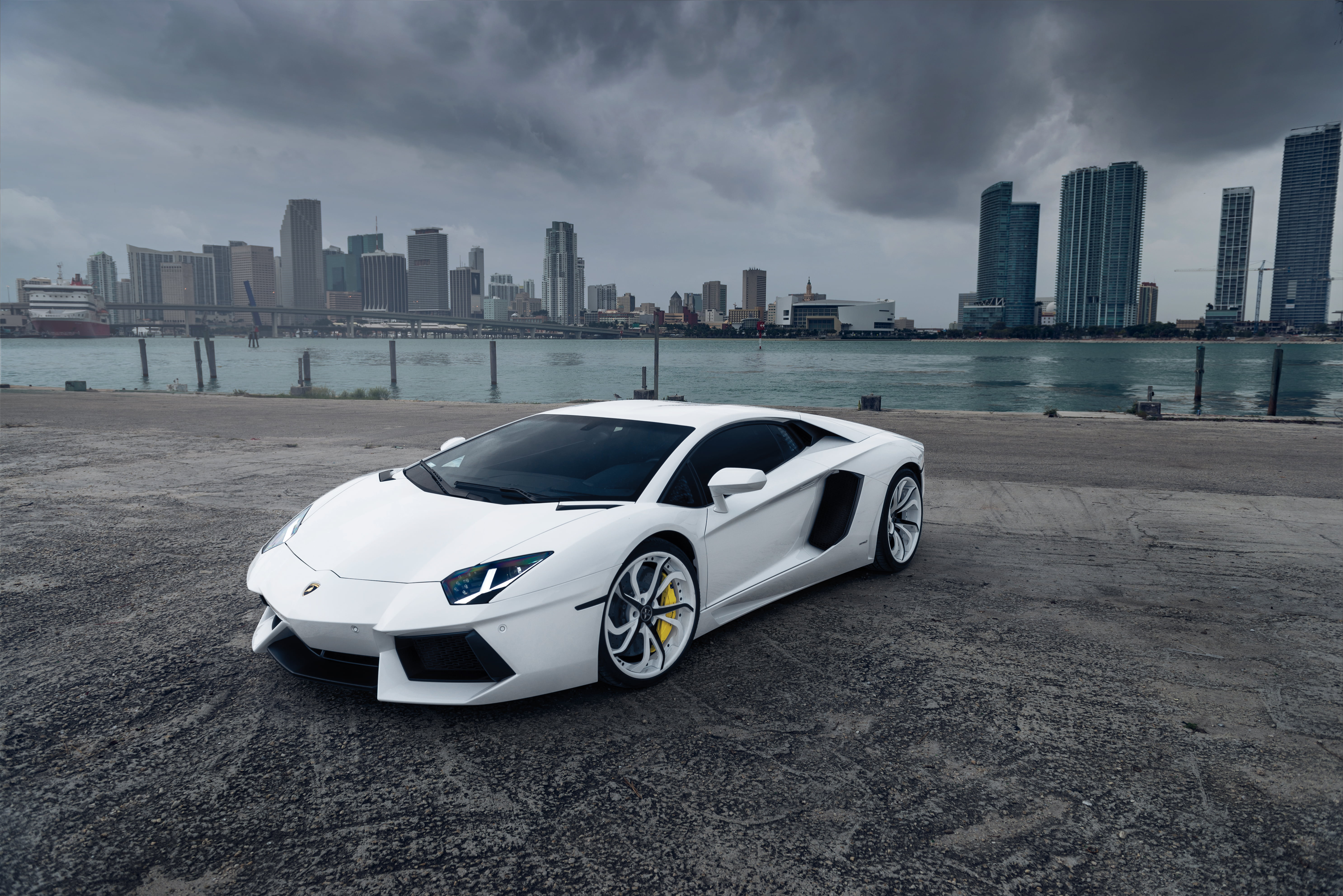office building exterior, sports, Aventador, outdoors, luxury, 5K, street, cloud - sky, road, supercar, new, no People, urban skyline, city, sky, parking Lot, HD Wallpaper