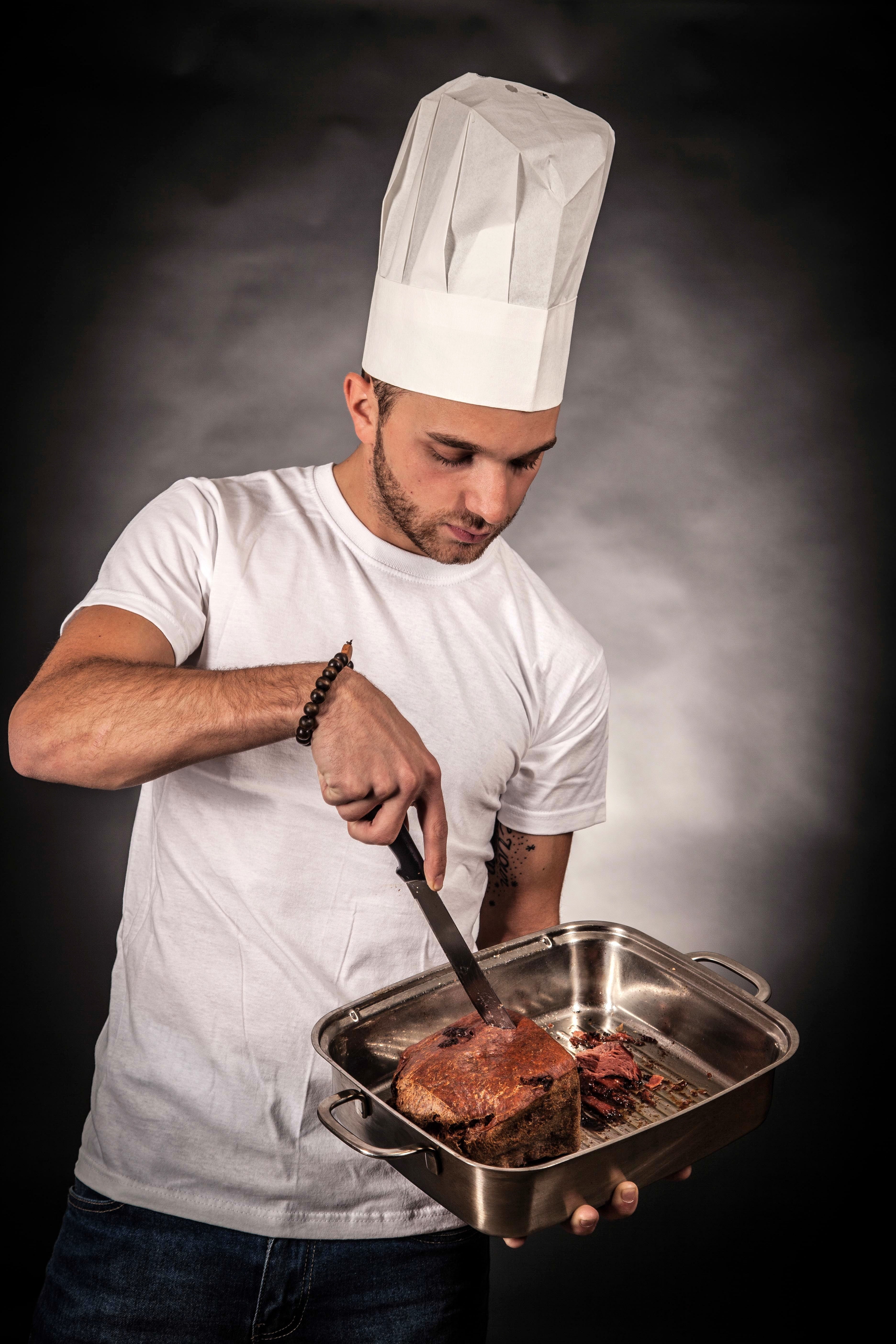 man, kitchen utensil, indoors, hat, chefs hat, person, young adult, one person, tong, 5K, restaurant, black background, standing, meat, preparing food, Phone HD Wallpaper