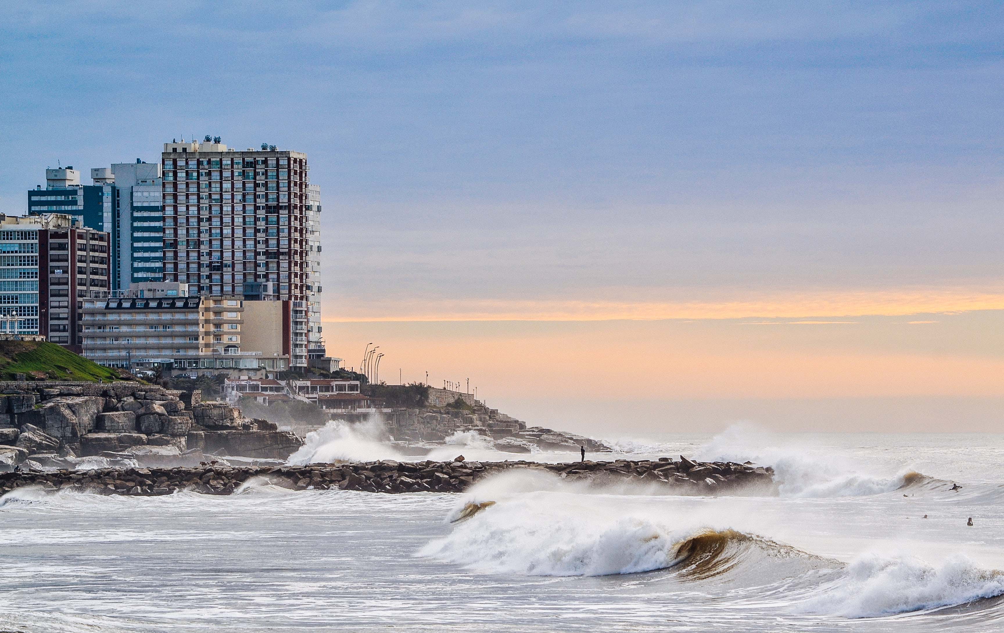 built structure, high, skyscraper, rise, cloud - sky, near, sunset, splashing, sea, 2K, no people, seashore, city, body, outdoors, architecture, waterbreak, HD Wallpaper