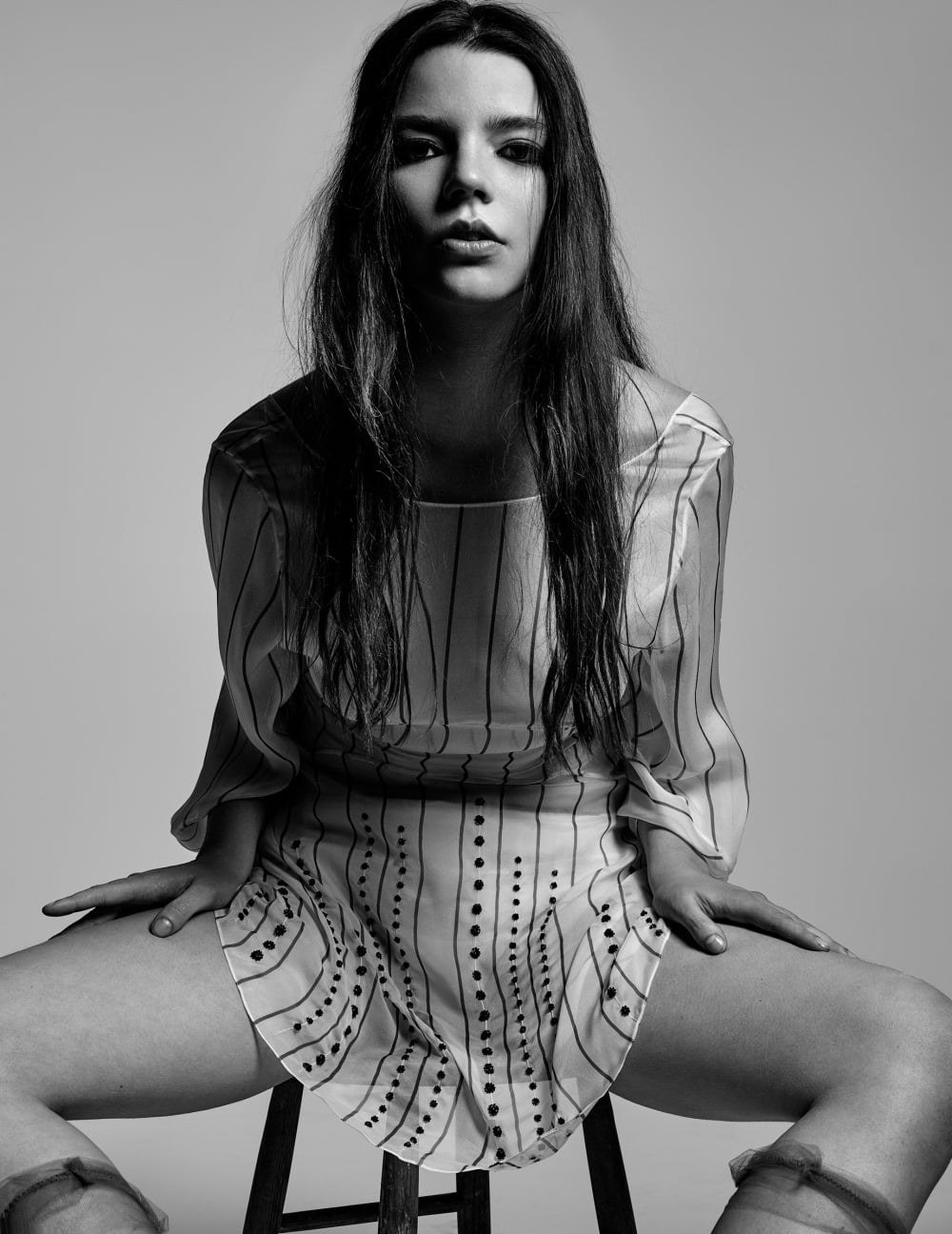 monochrome, actress, Anya Taylor-Joy, spread legs, long hair, brunette, women, simple background, dark hair, sitting, 720P, Phone HD Wallpaper