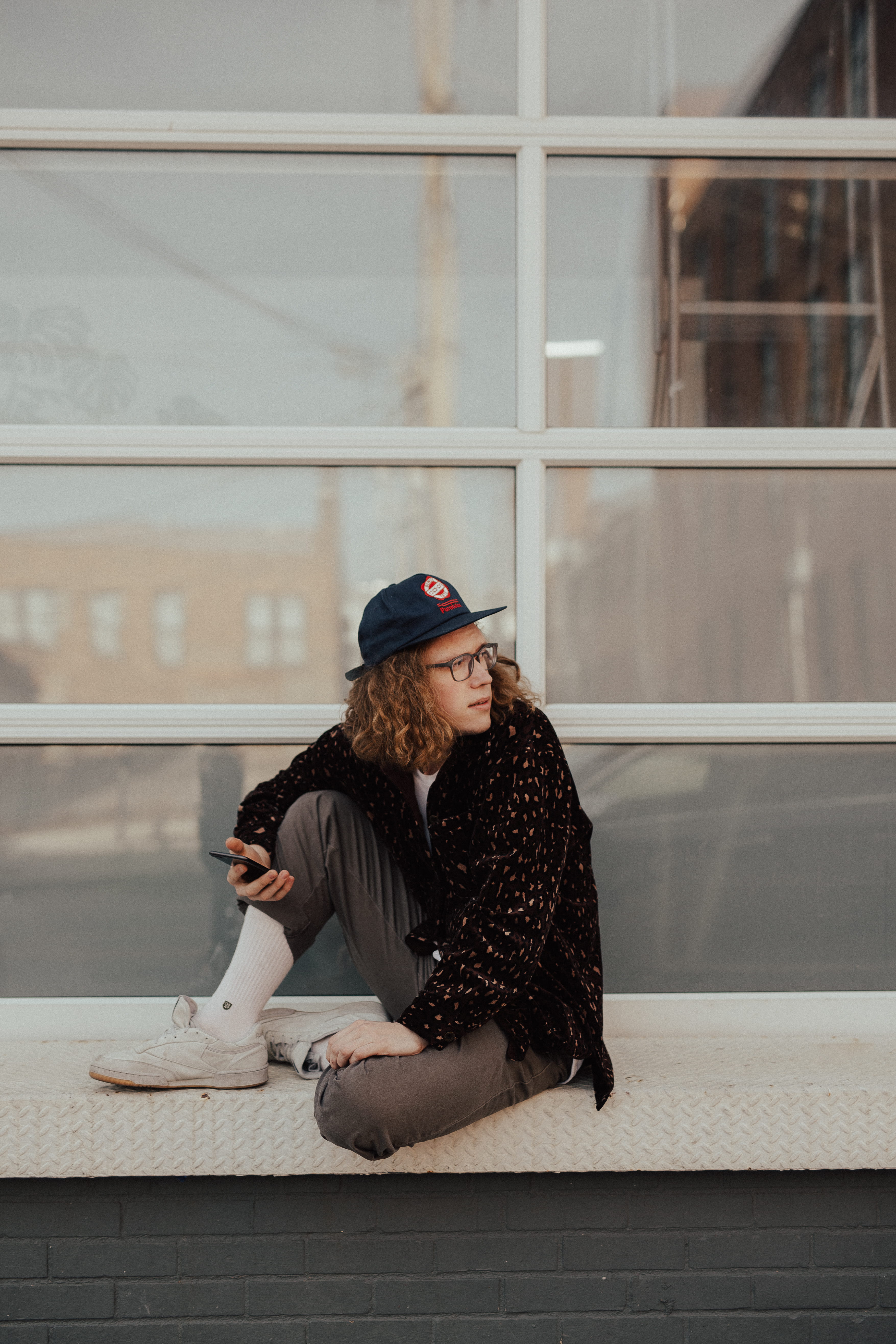 one person, casual clothing, left, glasses, beside, warm clothing, 5K, hat, full length, winter, sitting, millenial, curly hair, architecture, iphone, Phone HD Wallpaper