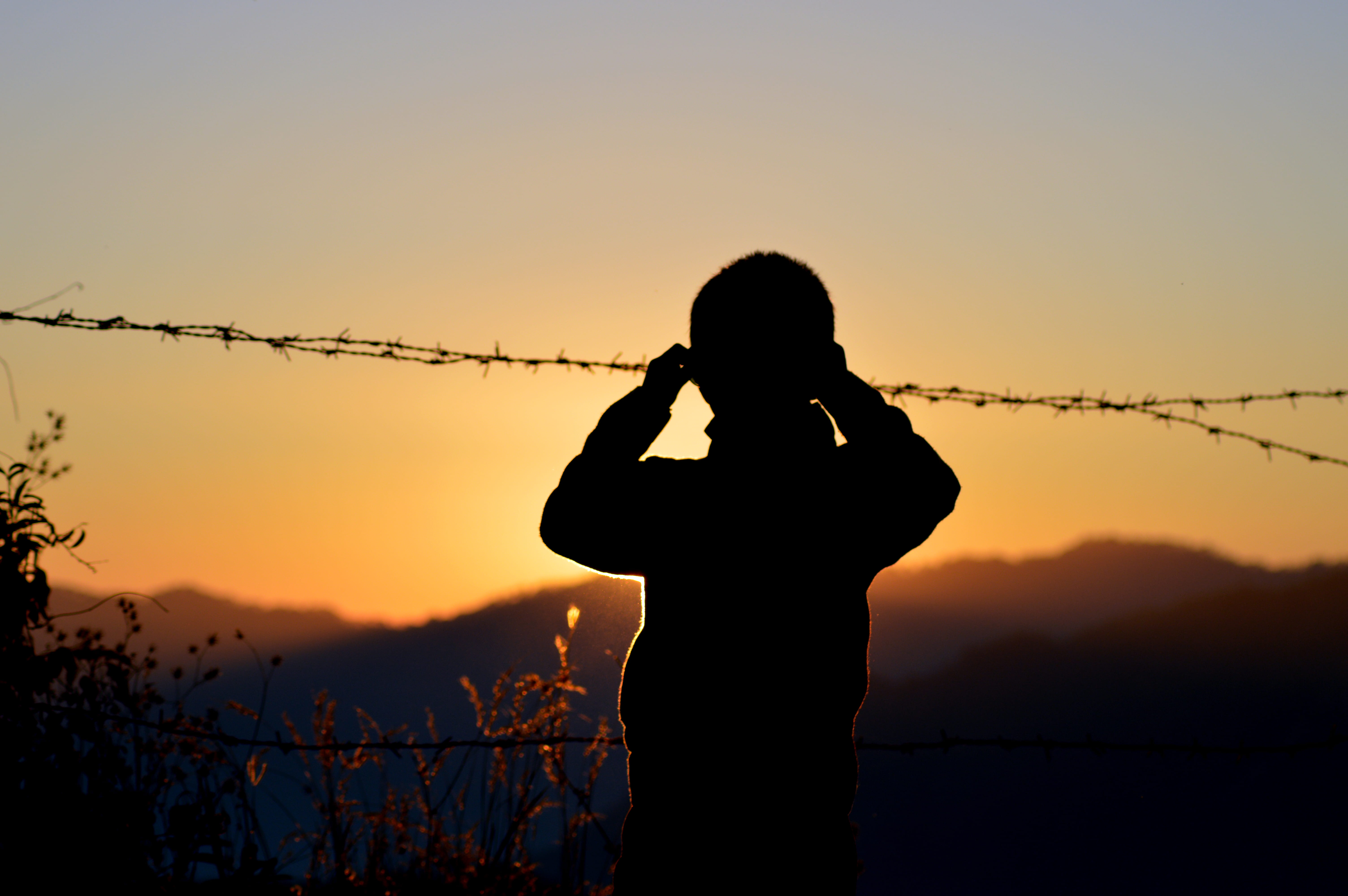 barbed wires, silhouette, adult, fence, wire, sunrise, orange color, outdoors, sunset, real people, three quarter length, technology, holding, idyllic, HD Wallpaper