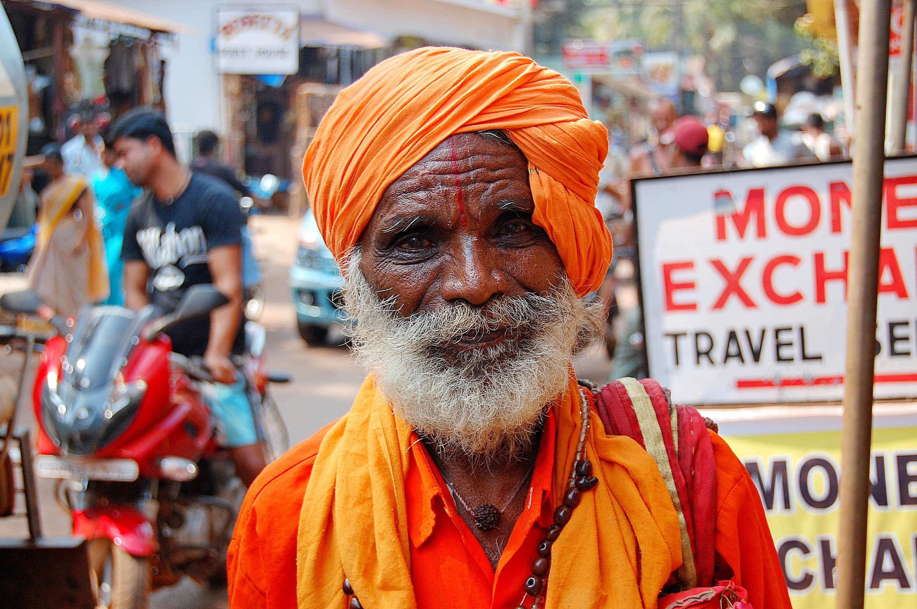 moped, adult, portrait, facial hair, person, focus on foreground, mature adult, looking at camera, street, indian, 2K, photo, wrinkles, real people, orange color, HD Wallpaper