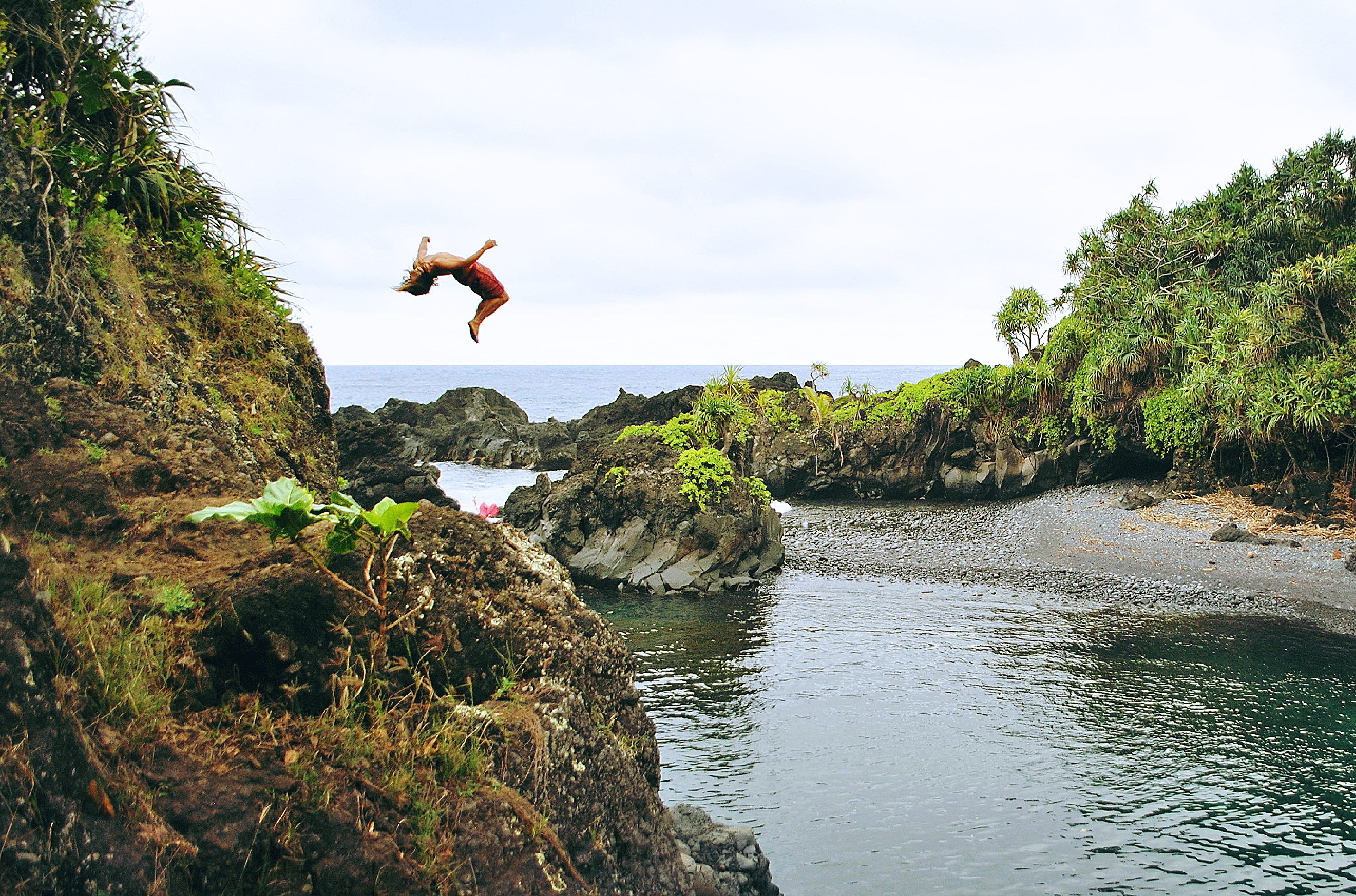 mid-air, rock, jumping, day, sky, nature, backflip, rock - object, one person, human arm, full length, formation, leisure activity, ocean, back, woman, HD Wallpaper