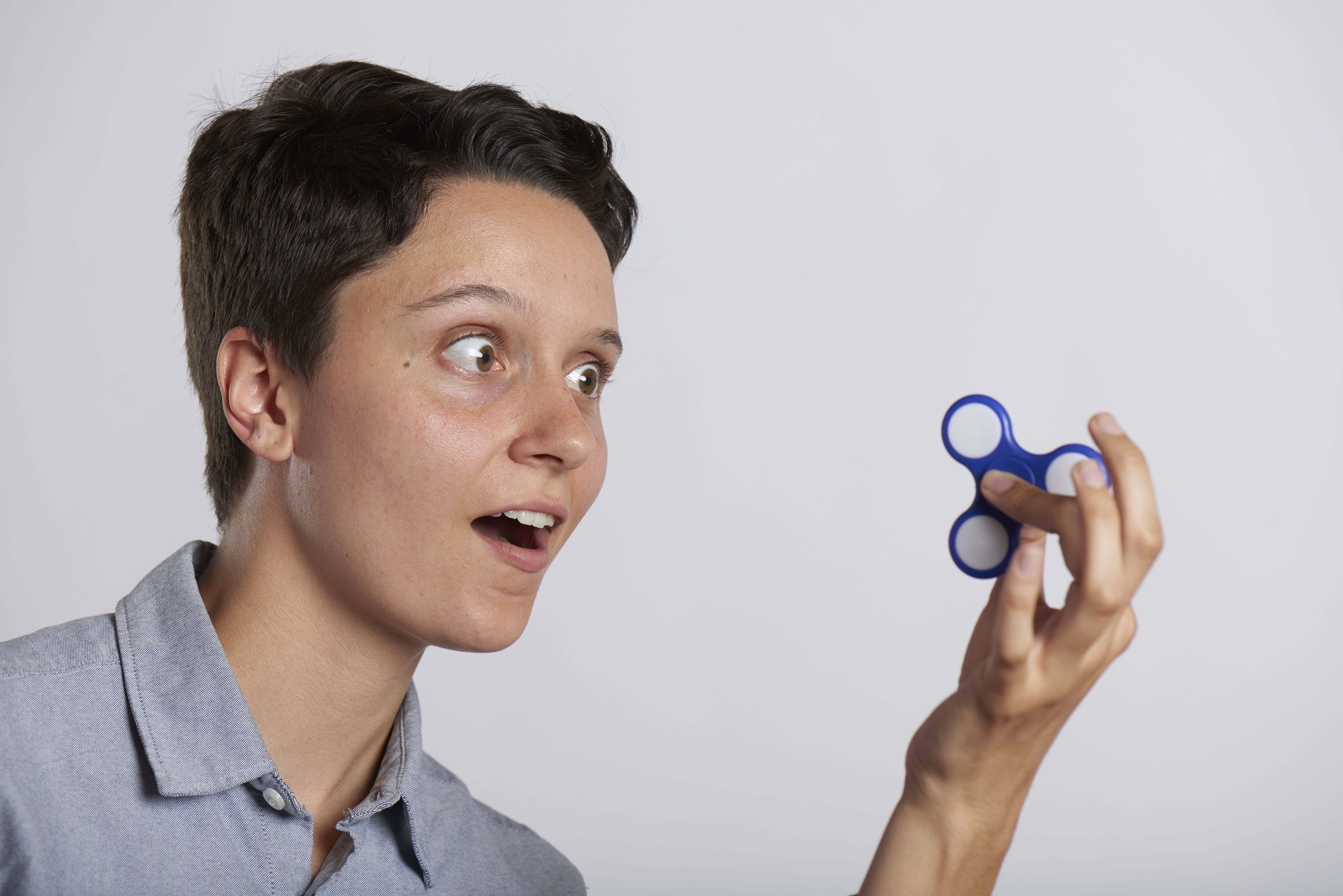 smiling, relaxation, gray background, fun, spinner, fad, human body part, business, body part, stress, indoors, play, game, hobby, finger, craze, holding, HD Wallpaper