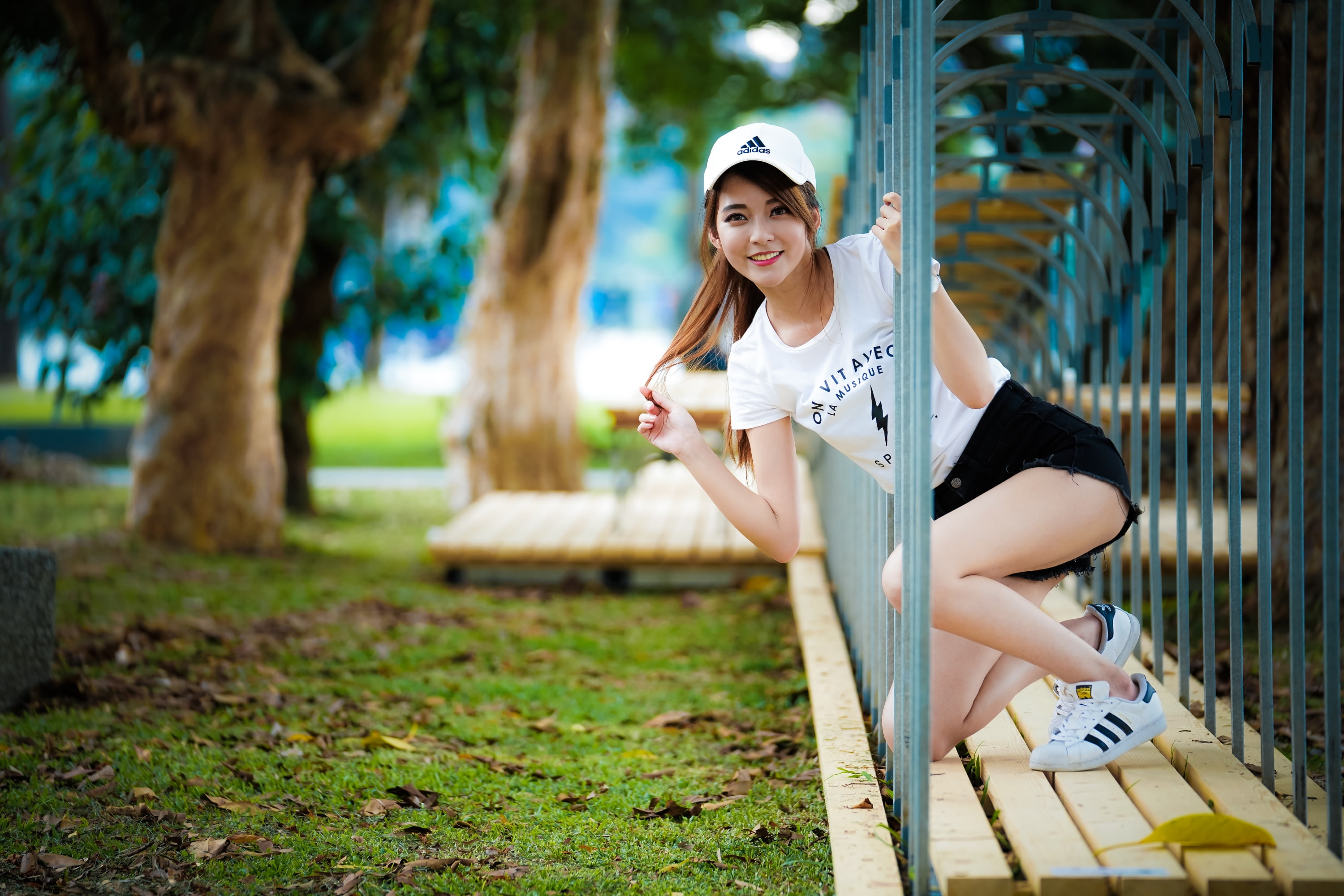 Asian, 2K, depth of field, touching hair, trees, baseball caps, women, brunette, T-shirt, looking at viewer, jean shorts, women outdoors, sneakers, smiling, HD Wallpaper