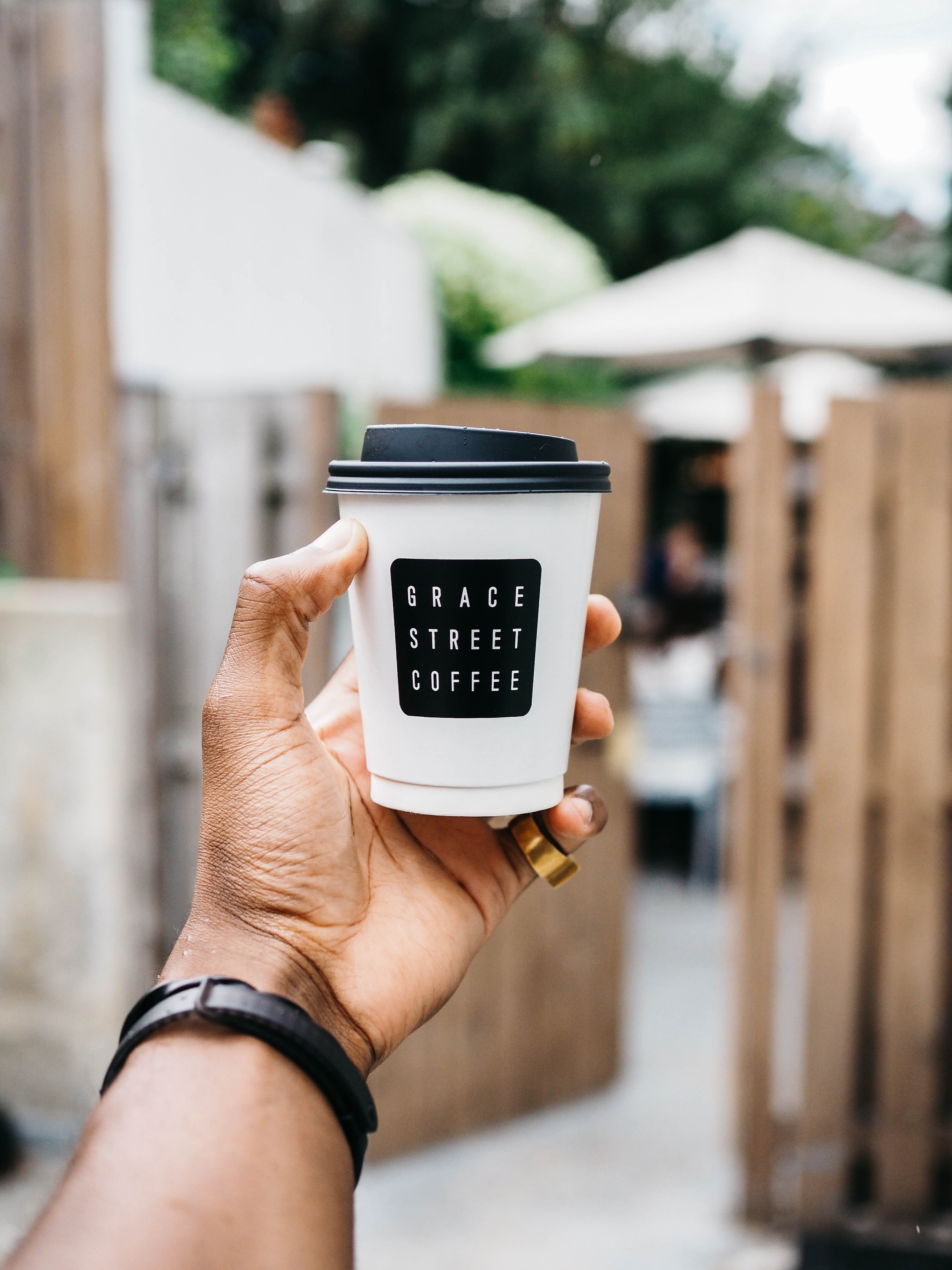 focus on foreground, gate, real people, communication, street, 4K, close-up, drink, human hand, latte, person, outdoors, wireless technology, technology, Phone HD Wallpaper