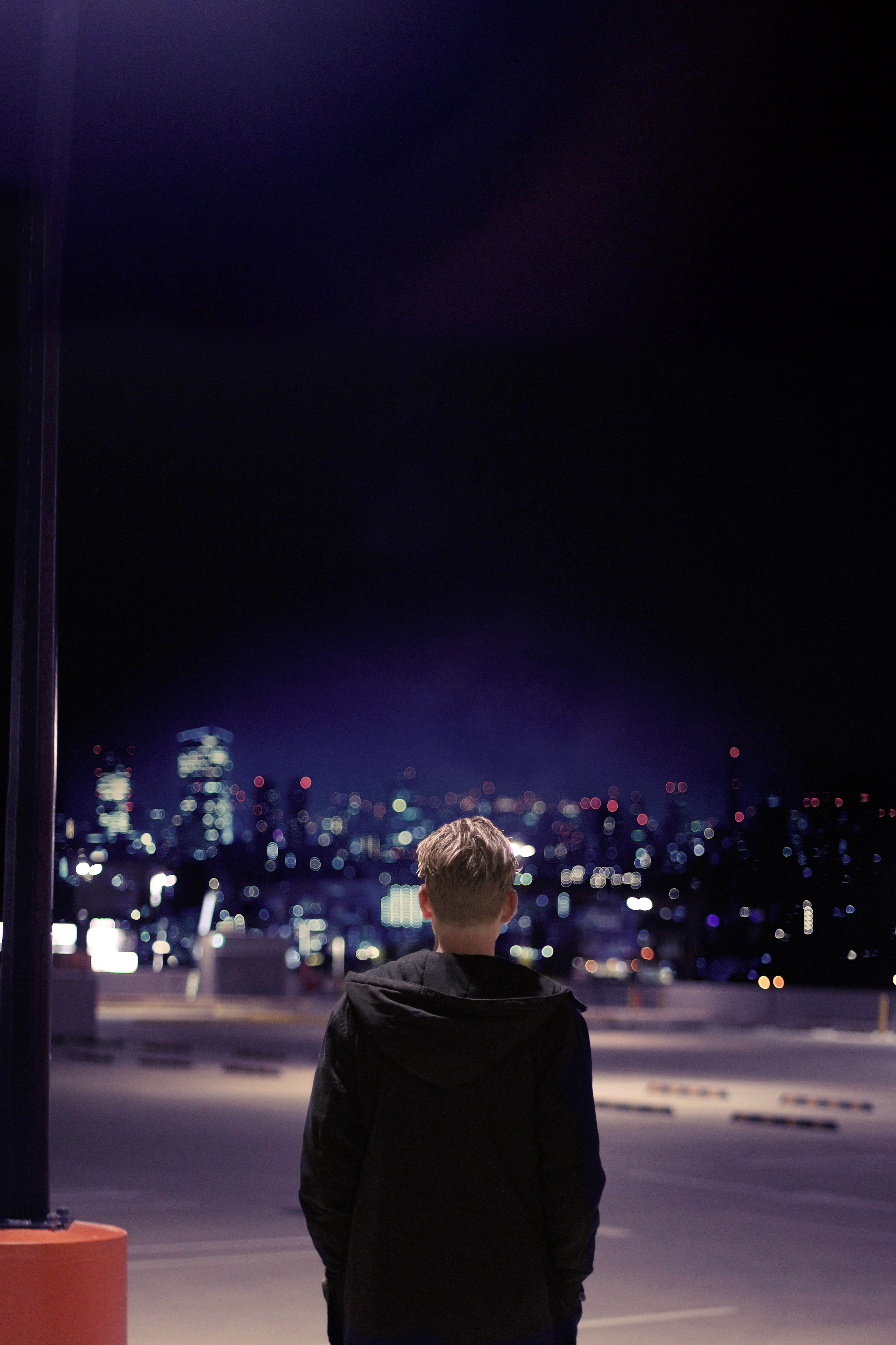 young adult, illuminated, bokeh, dark, urban, sky, night, jacket, men, real people, lifestyles, sidewalk, one person, one man only, looking at view, focus on foreground, Phone HD Wallpaper
