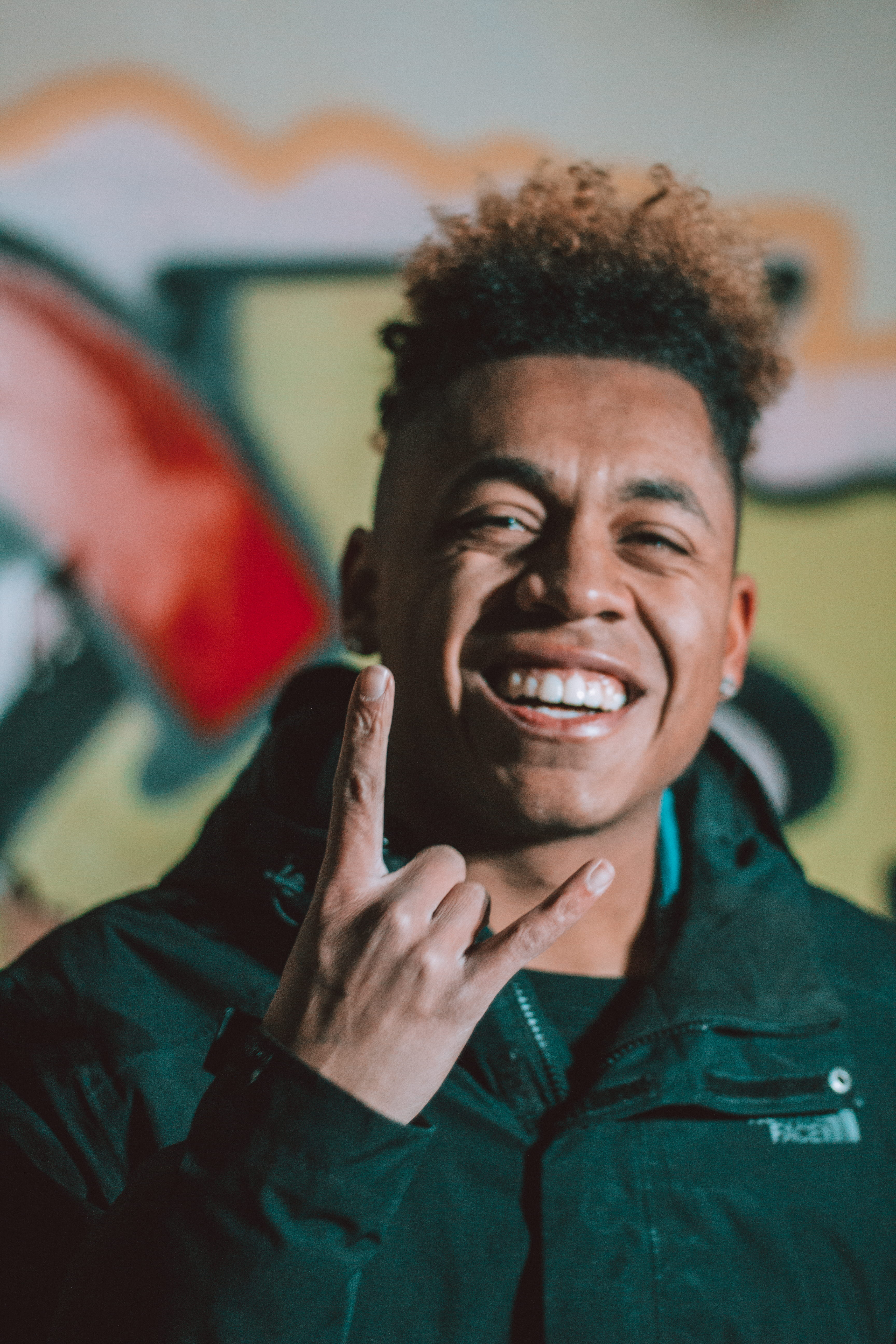 horn, person, lifestyles, gesturing, looking at camera, 5K, real people, rock, roll, indoors, happiness, teeth, jacket, focus on foreground, man, hairstyle, Phone HD Wallpaper