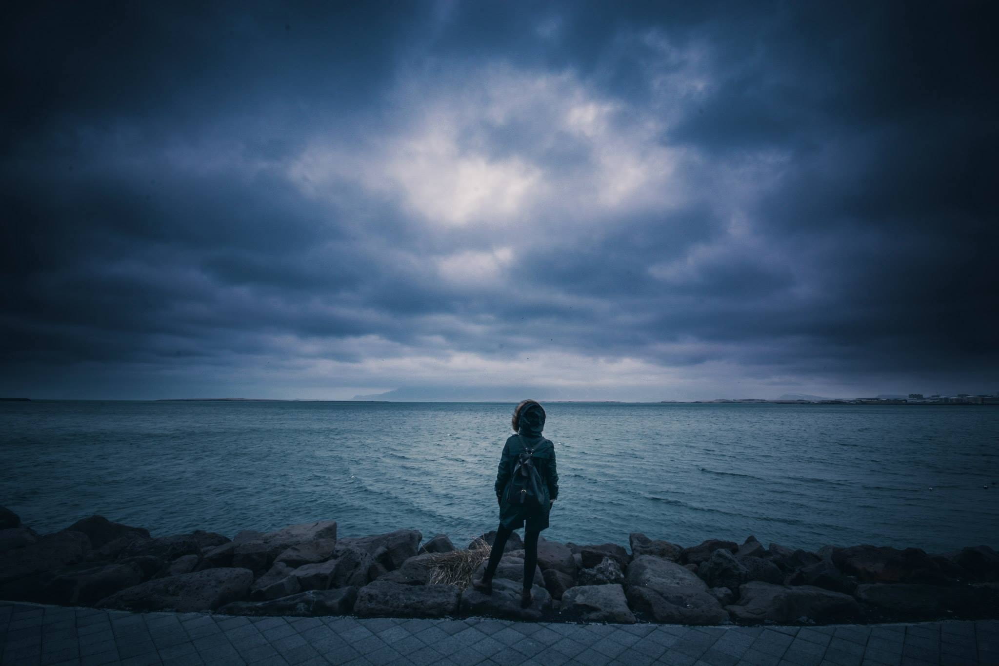 leisure activity, sea, standing, female, person, water, shore, clouds, ocean, young, roadside, back, full length, land, looking, nature, lifestyles, stones, HD Wallpaper