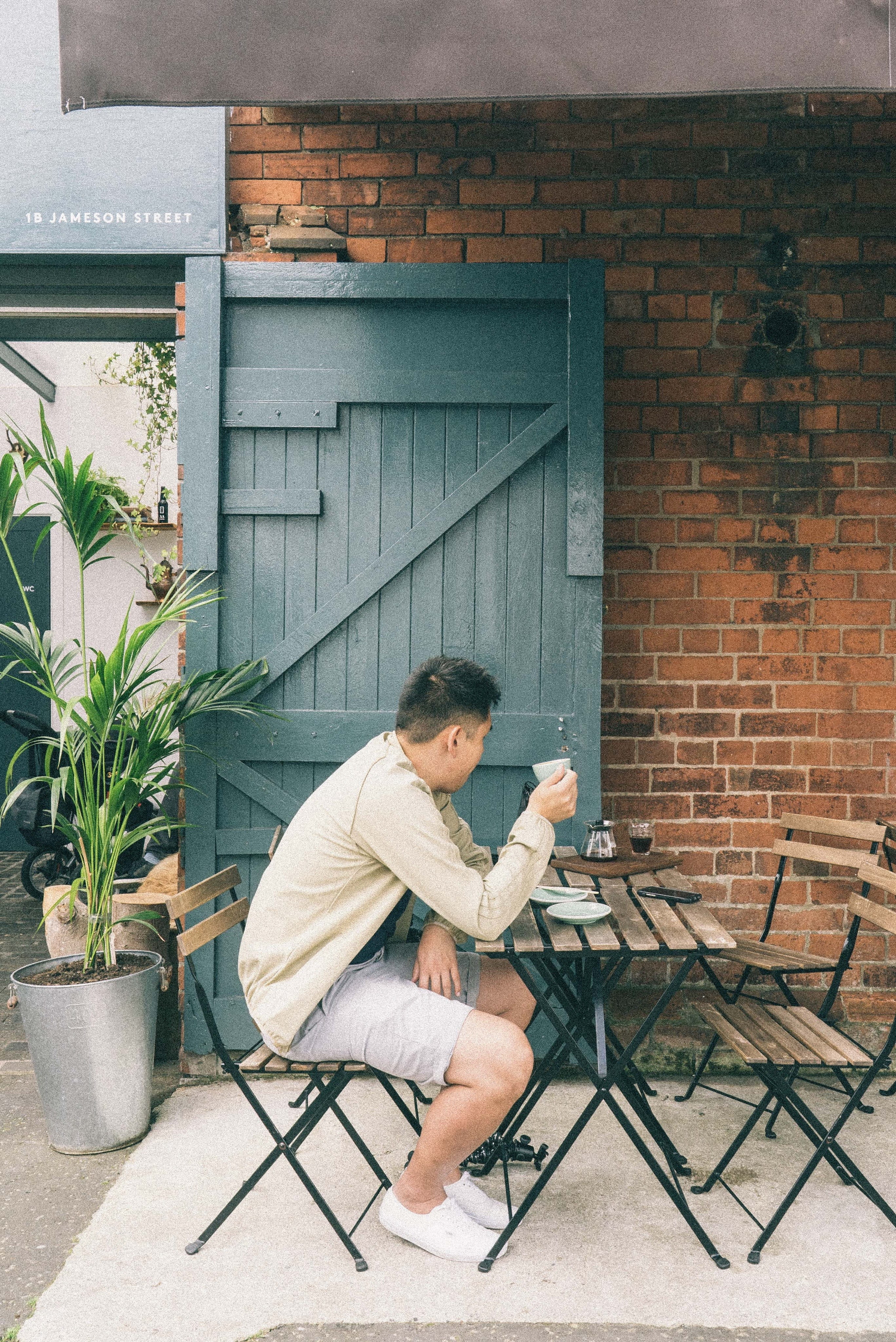building exterior, outdoors, door, person, restaurant, built structure, man, food and drink, lifestyles, seat, leisure activity, pants, undershirt, sitting, Phone HD Wallpaper