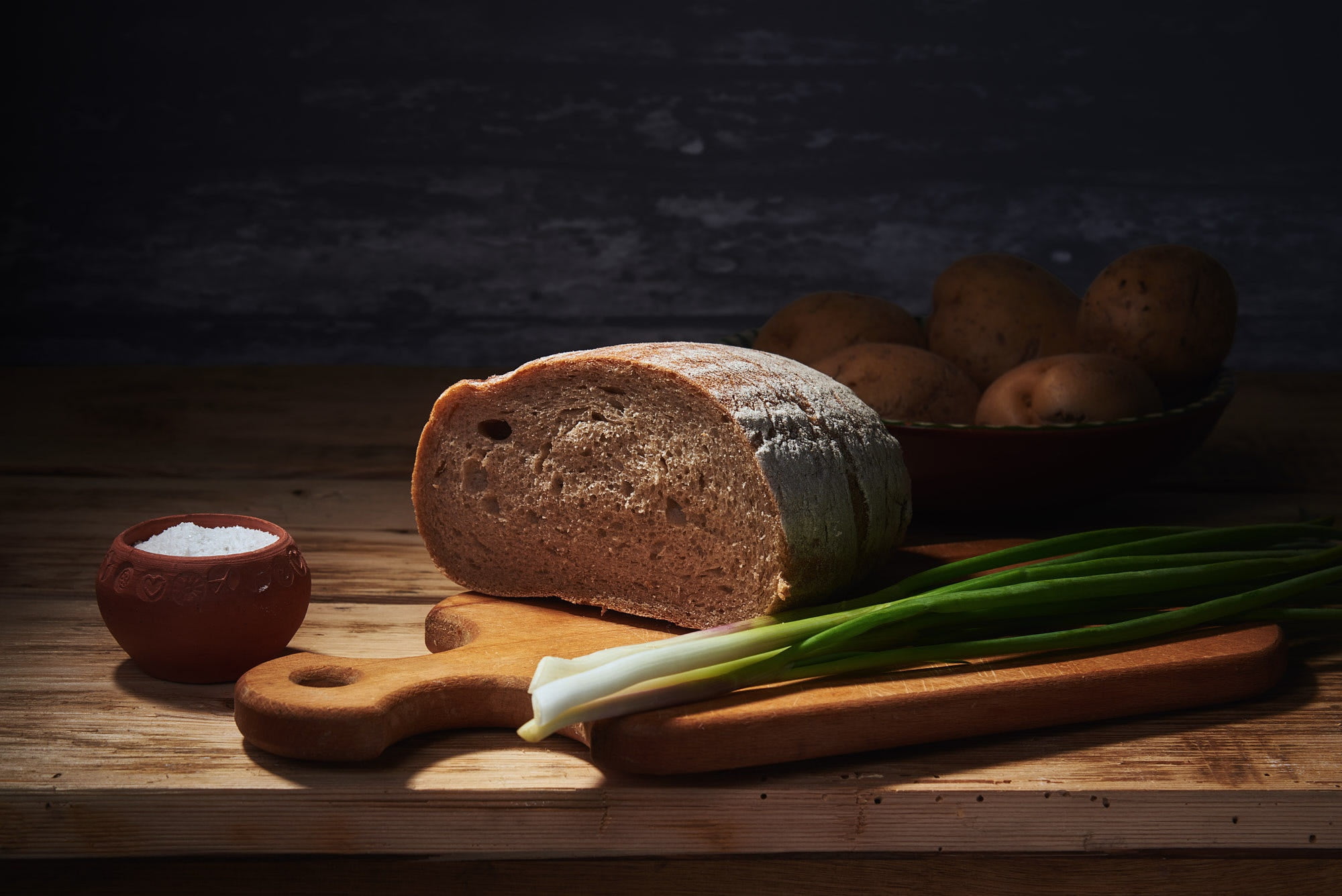 the dark background, green, items, dishes, cutting Board, food, table, bow, 1080P, light, potatoes, bread, salt shaker, pen, salt, still life, vegetables, HD Wallpaper