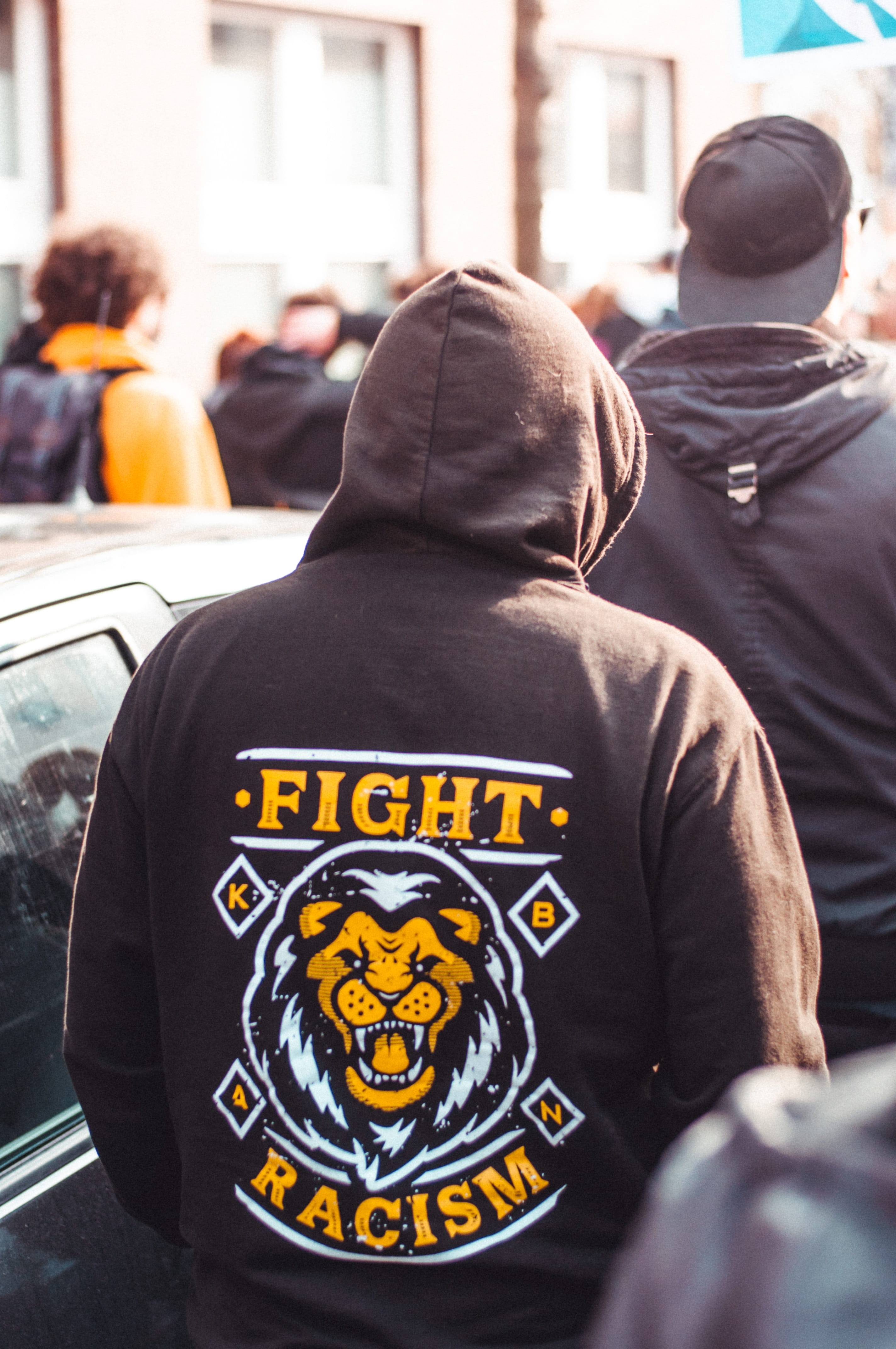 focus on foreground, real people, men, stop racism, cap, apparel, back, berlin, lion, group of people, fight racism, demonstration, day, outdoors, hood, Phone HD Wallpaper