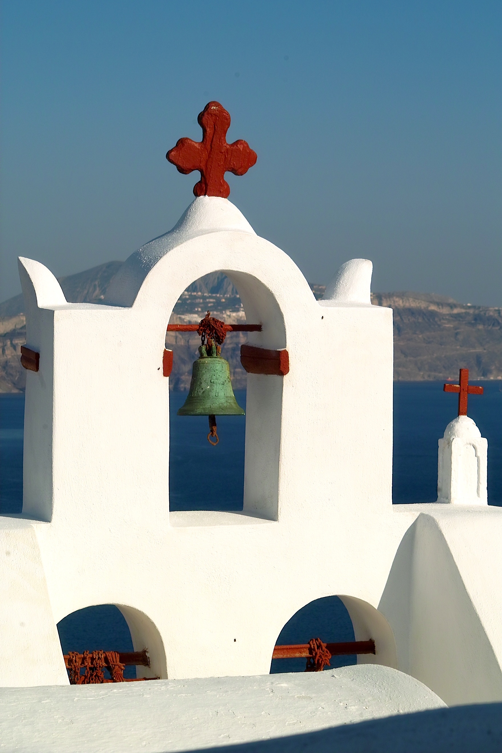 sky, volcano, 2K, building exterior, santorini, sunlight, travel, island, bell, belief, cross, aeolian island, built structure, sea, arch, place of worship, Phone HD Wallpaper