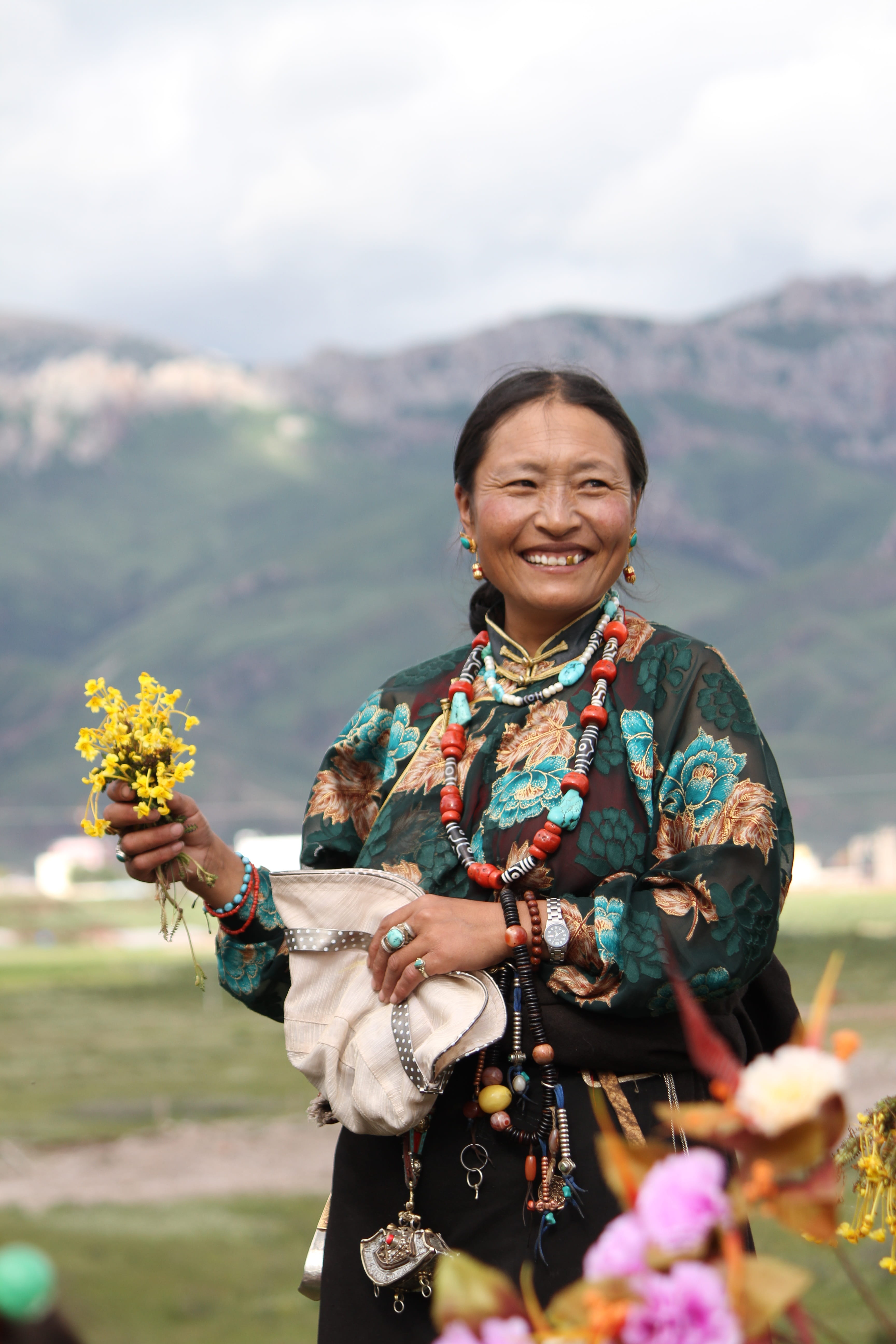hand holding flowers, standing, leisure activity, smiling, one person, lifestyles, real people, happiness, only women, plant, flowering plant, tibet ethnic, Phone HD Wallpaper