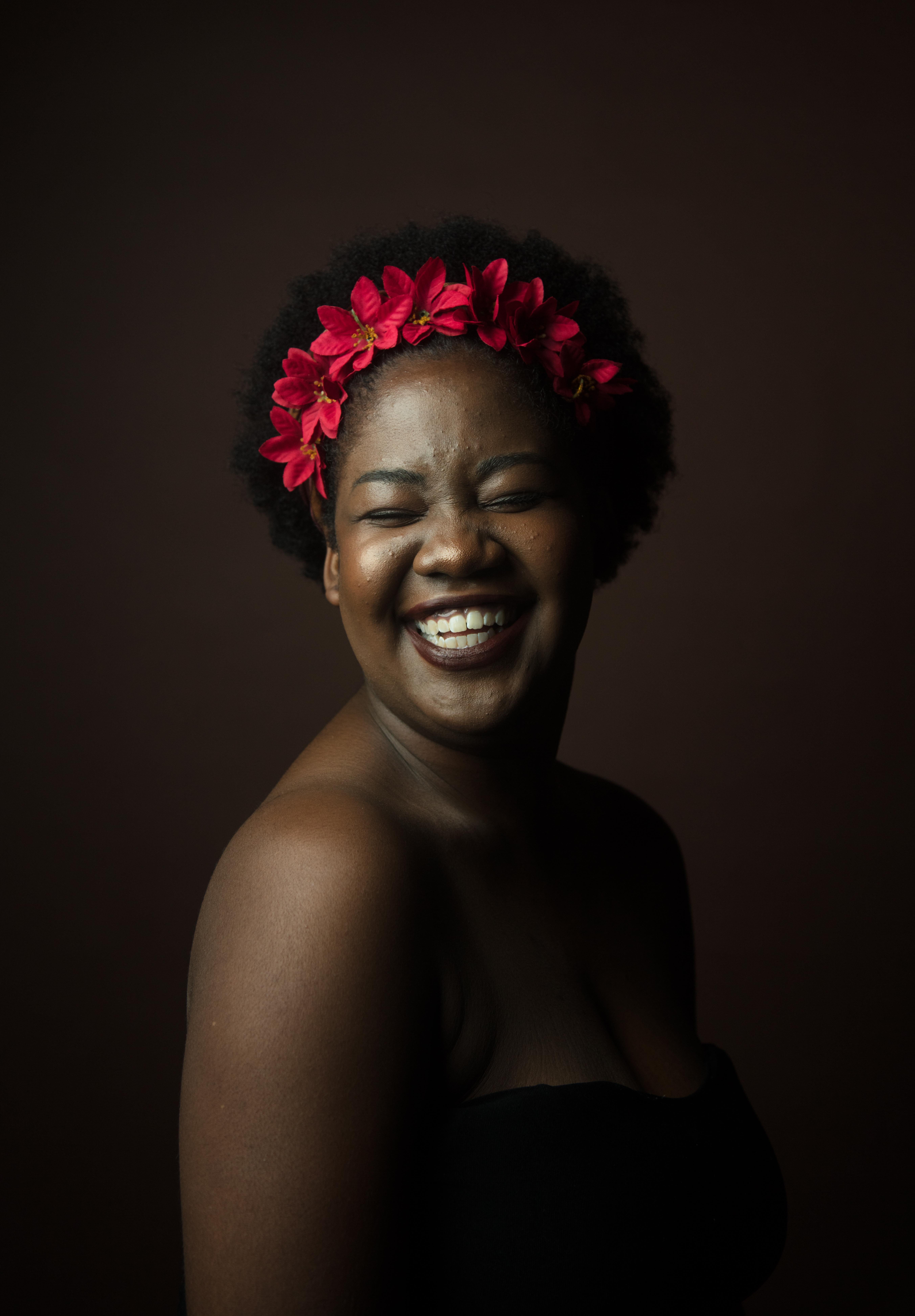 focus, smile, black background, woman, smiling, toothy smile, flowers, black woman, flowering plant, hairstyle, eyes closed, laugh, floral, studio, beautiful woman, Phone HD Wallpaper