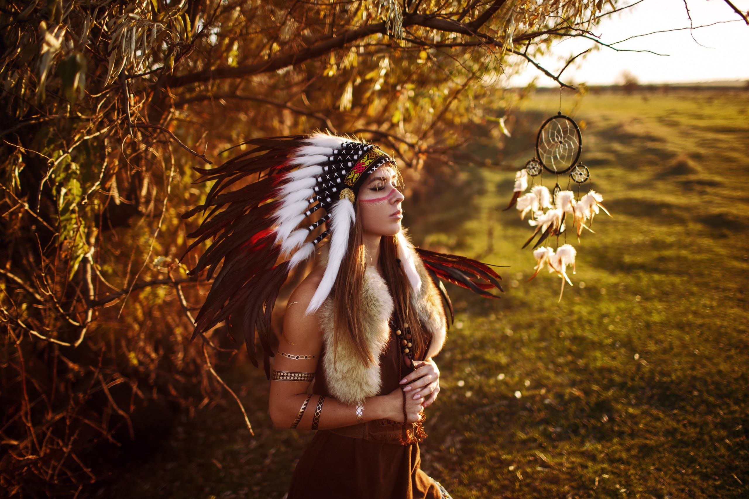 amulet, closed eyes, branches, coloring, feathers, decoration, trees, 2K, headdress, brown hair, field, landscape, bokeh, fur, Dreamcatcher, girl, outfit, HD Wallpaper