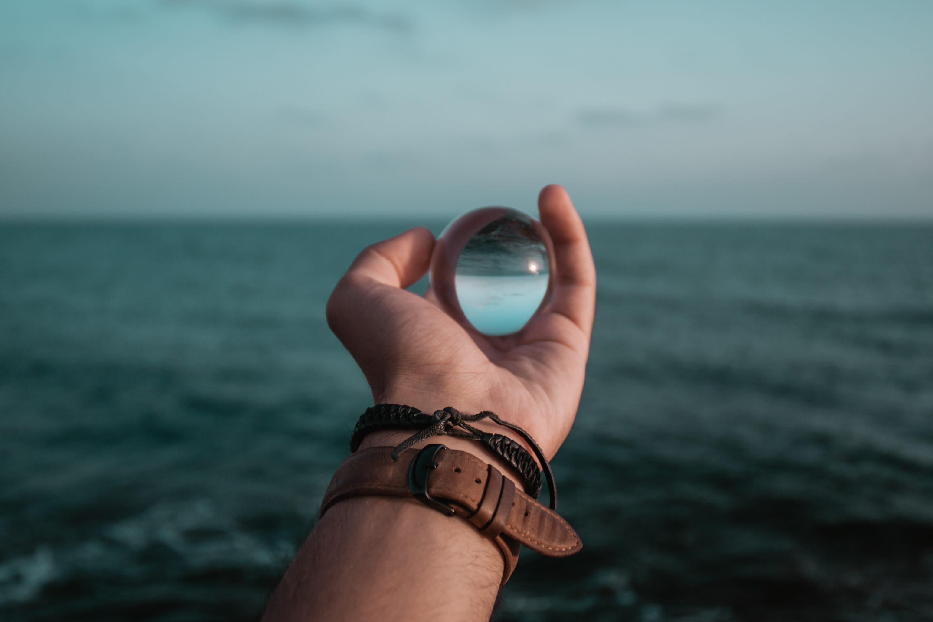 horizon over water, water, 2K, sea, strap, nature, holding, hand, travel, human body part, man, body part, sky, globe, watch, real people, human finger, HD Wallpaper