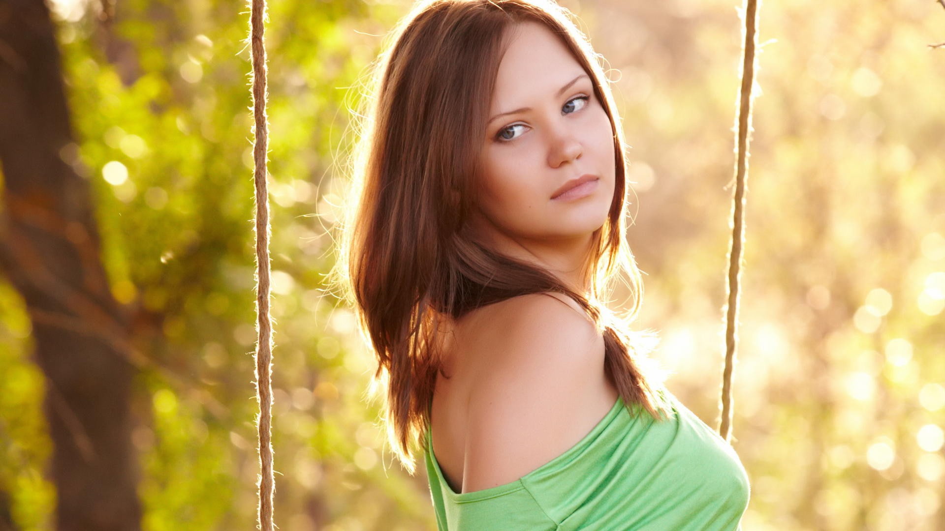 green dress, looking away, ropes, Ariel B, trees, model, long hair, brunette, bokeh, 1080P, women, sunlight, face, swings, bare shoulders, women outdoors, HD Wallpaper