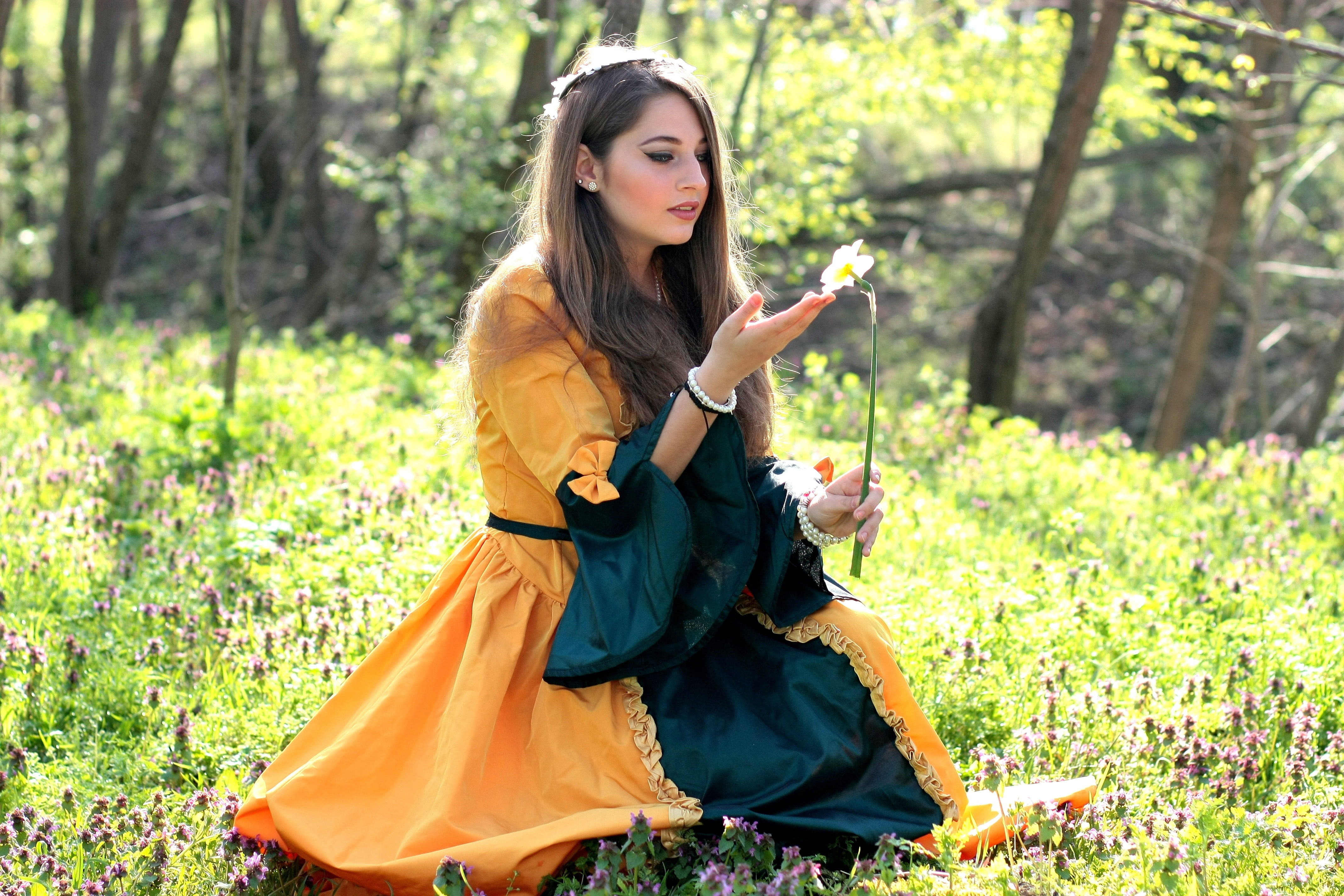 females, long hair, outdoors, field, princess, blue, dress, flower, sitting, orange, women, hairstyle, one person, spring, sits, story, petaled, brown hair, HD Wallpaper