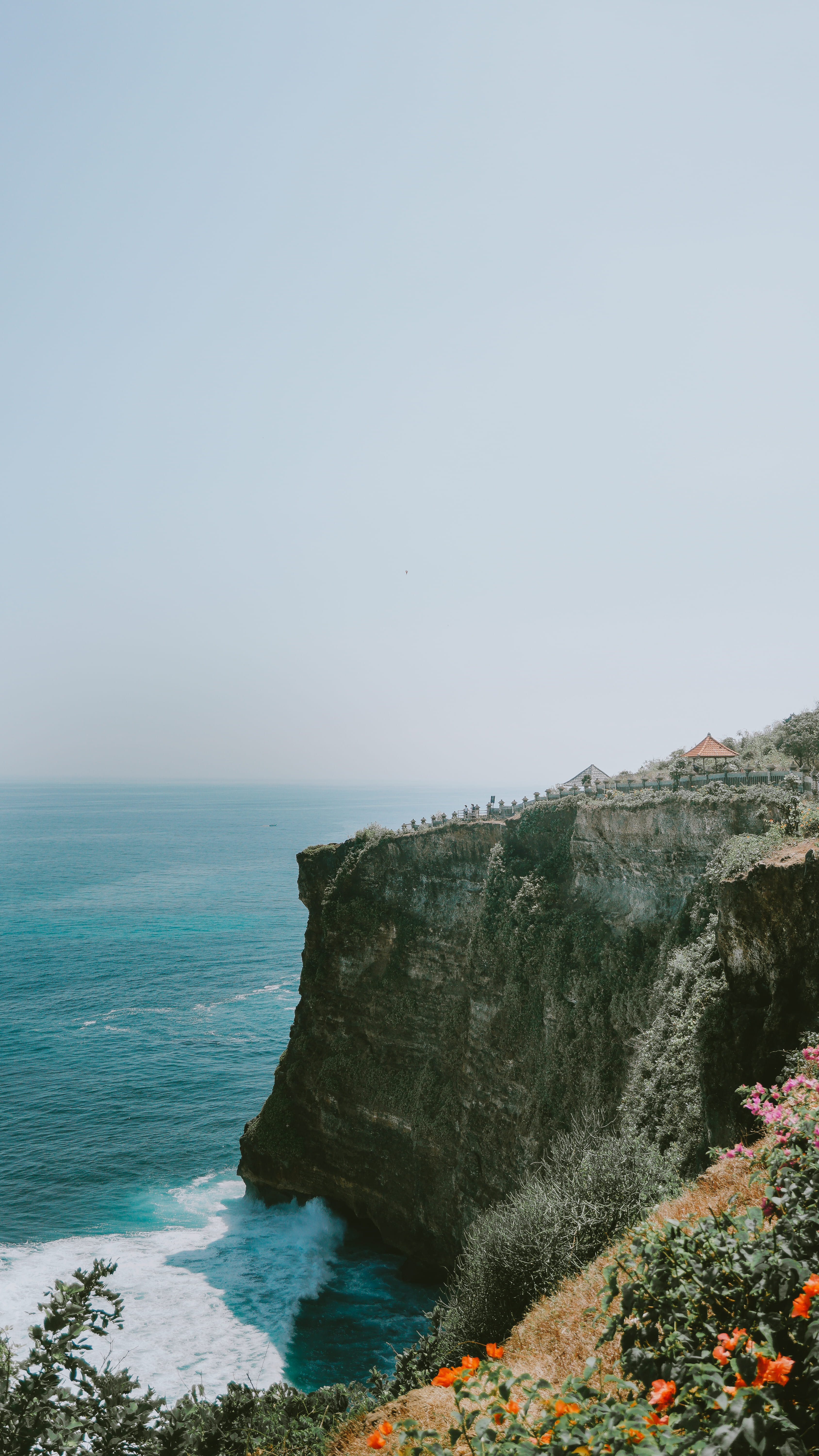 conifer, rocky coastline, plant, sunlight, day, tranquility, flower, uluwatu temple, scenics - nature, shadow, cliff, outdoors, beauty in nature, rock - object, Phone HD Wallpaper