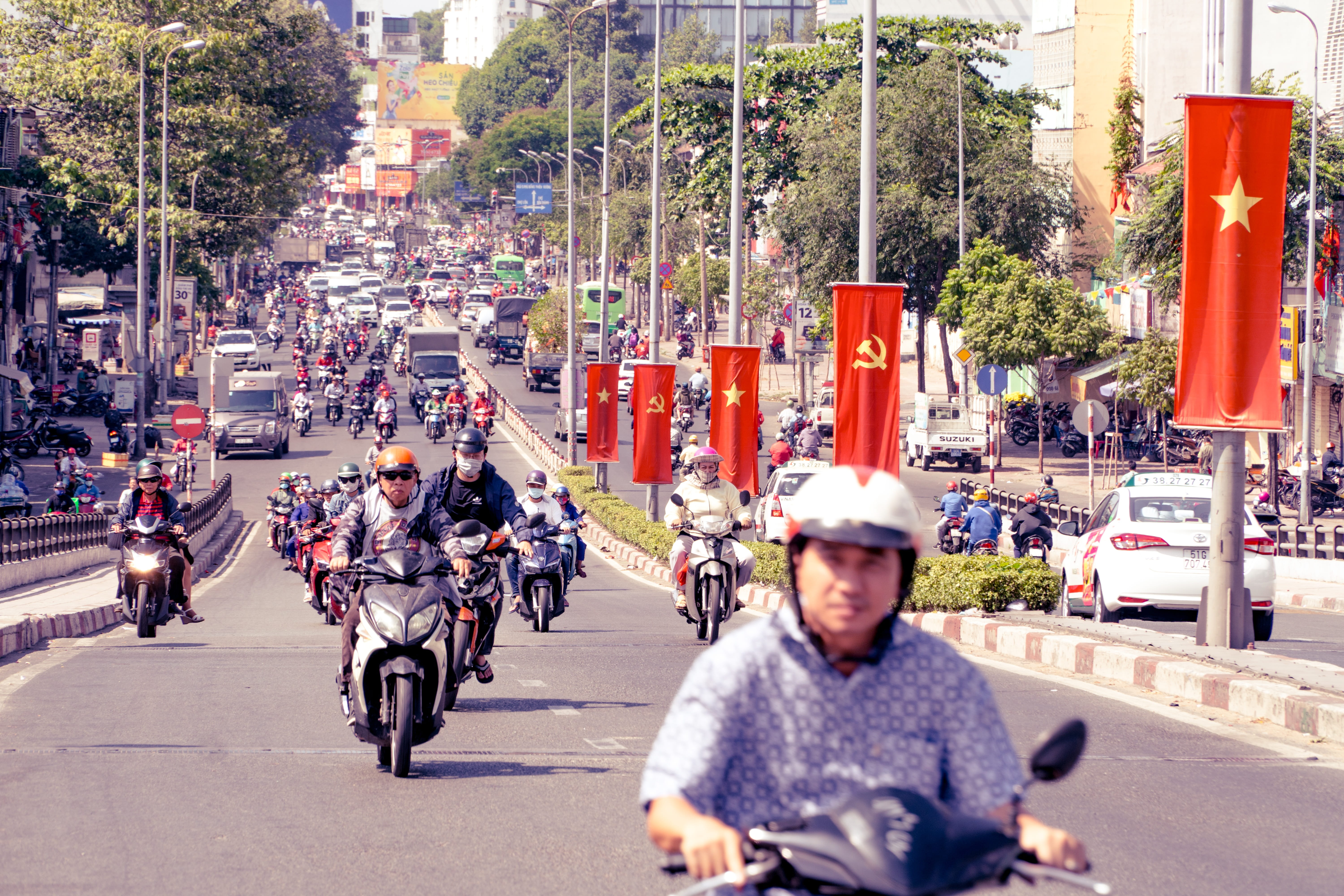 motorcycle, road transport, day, plant, architecture, city, lifestyles, traffic, vehicle, motor bike, flag, tree, crowded, real people, moto, helmet, protection, HD Wallpaper