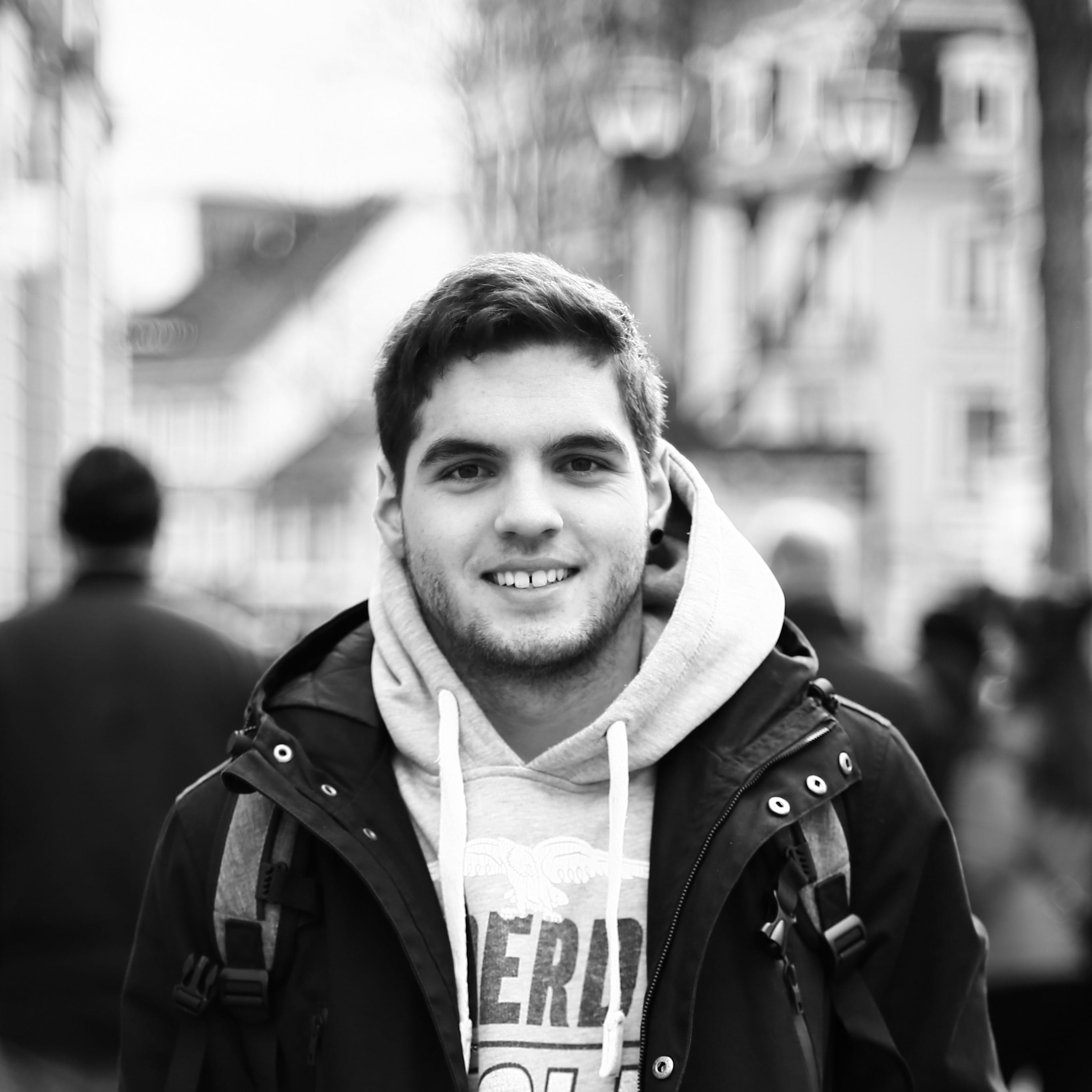black and white, 2K, winter, front view, street, uniform, focus on foreground, mulhouse, incidental people, white, backpack, smile, warm clothing, looking at camera, Phone HD Wallpaper