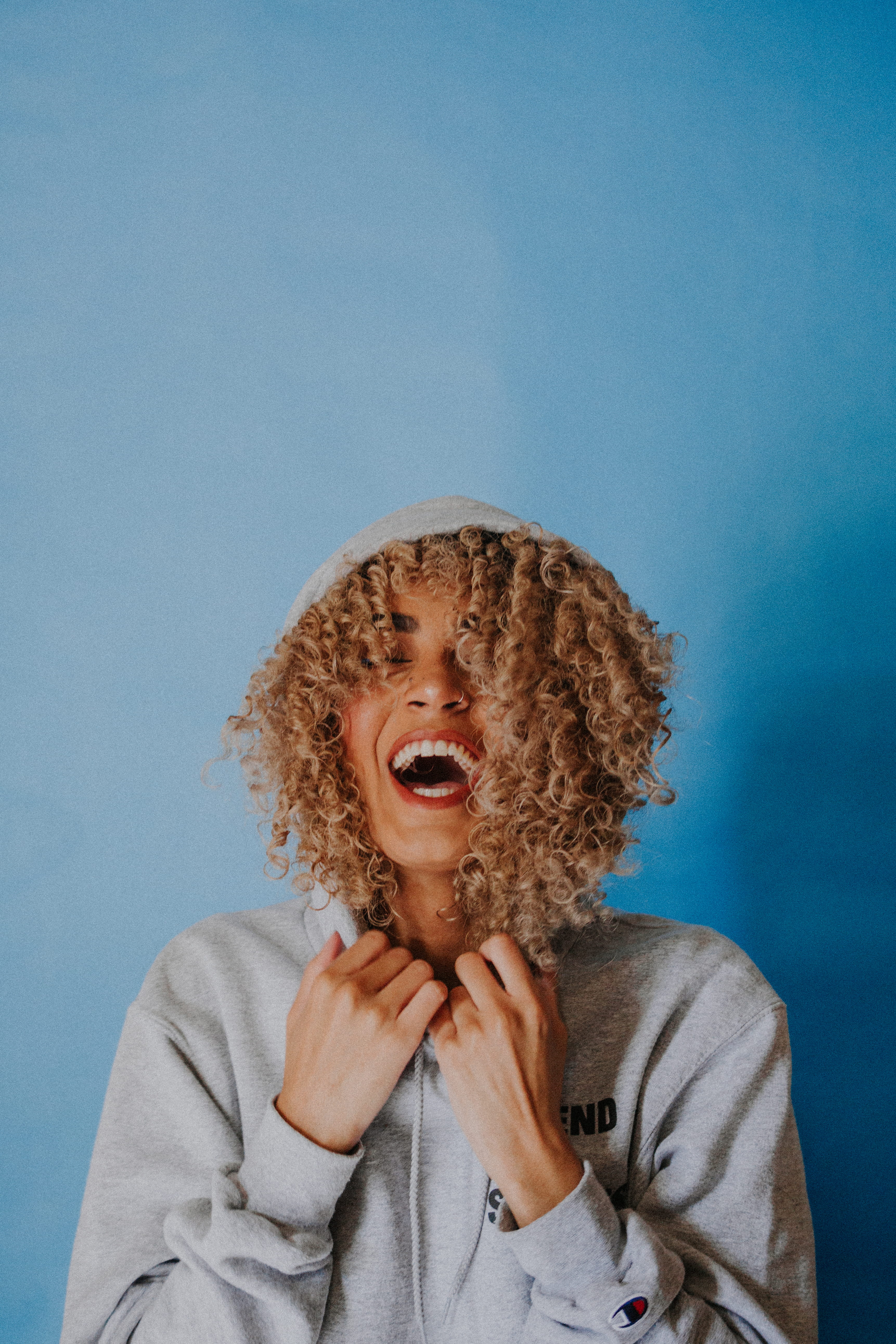 gray, laugh, blue, casual clothing, mouth open, smiling, sweater, woman, curly hair, wall - building feature, front view, portrait, hair, smile, wearing, Phone HD Wallpaper