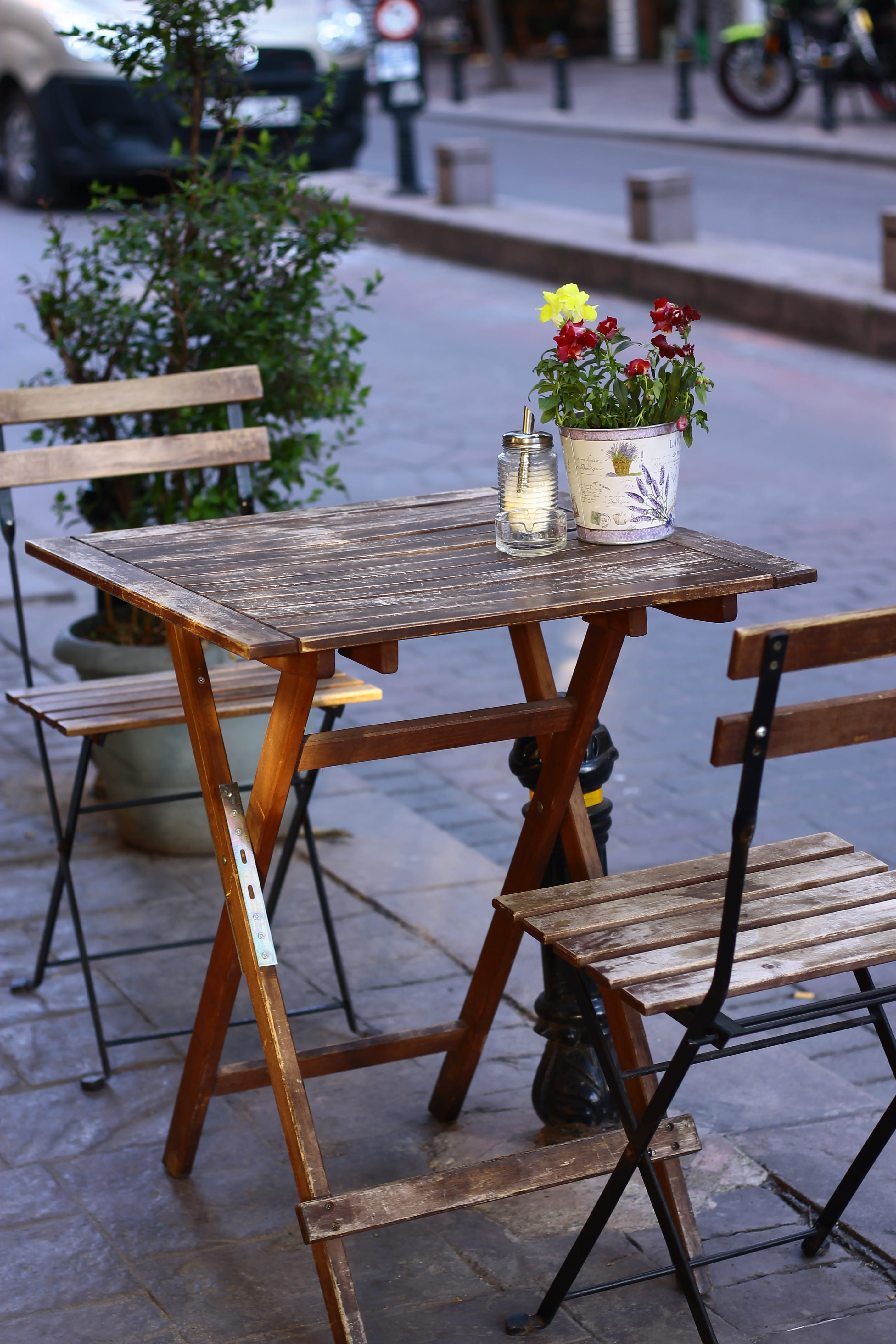 shallow, focus, no people, food and drink, furnitures, pot, empty, flowers, street, arrangement, wood - material, chair, absence, nature, seat, plant, sidewalk cafe, Phone HD Wallpaper