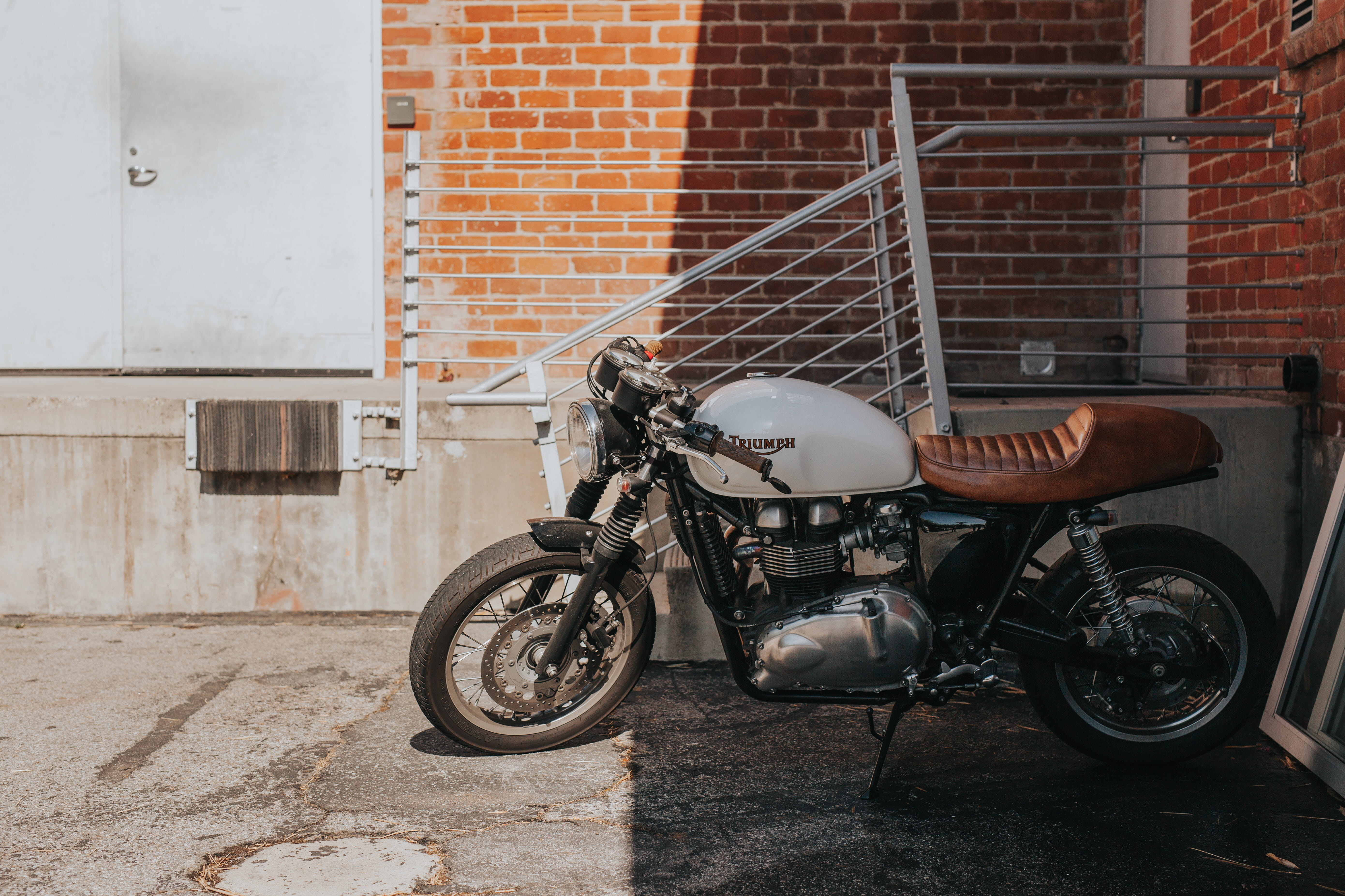 transportation, land vehicle, gray, bobber, BIKE, city, brick wall, beside, urban Scene, motorcycle, 5K, outdoors, no People, mode of transportation, built structure, HD Wallpaper