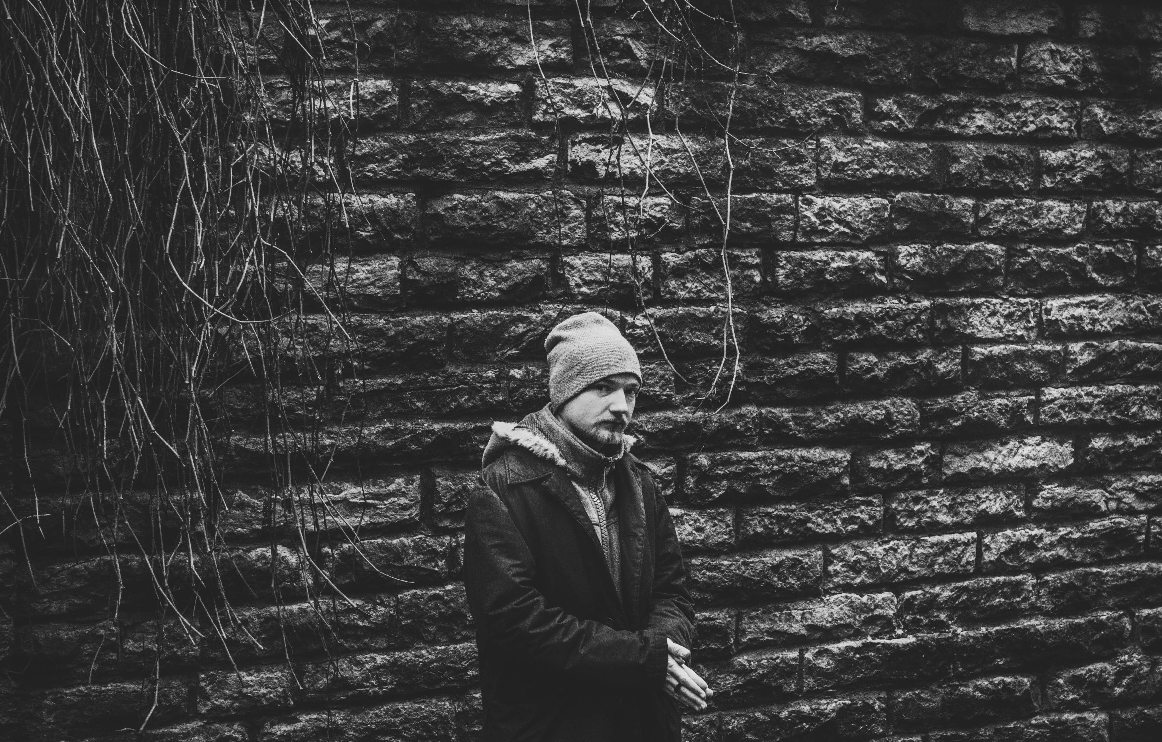 day, face, wall, man, dark, brick, stone wall, bonnet, black, clothing, facial expression, black and white, one person, brick walls, standing, outdoors, HD Wallpaper