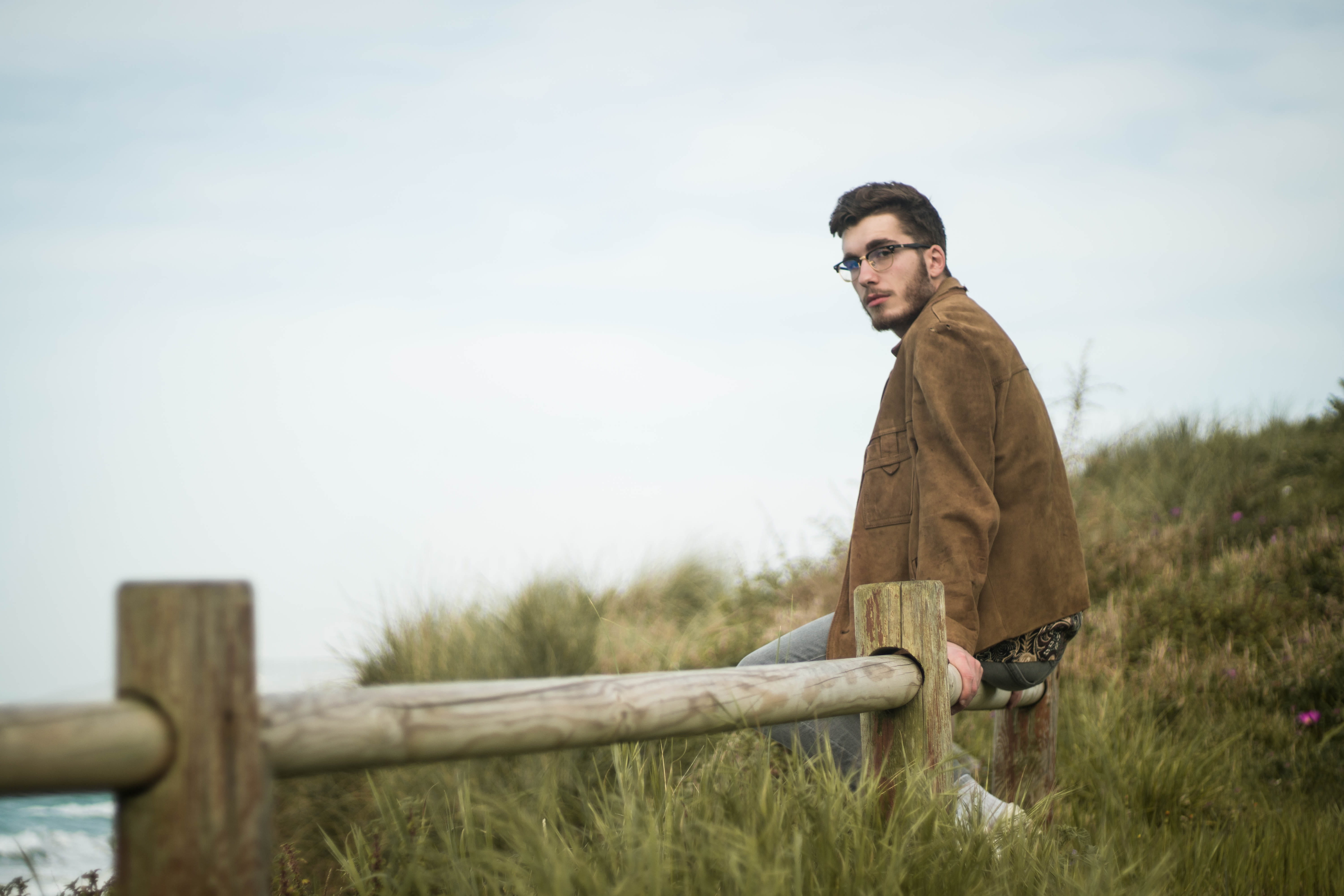 apparel, coat, wood - material, sky, plant, casual clothing, real people, sea, standing, one person, blazer, grass, sitting, 5K, young adult, jacket, three quarter length, HD Wallpaper