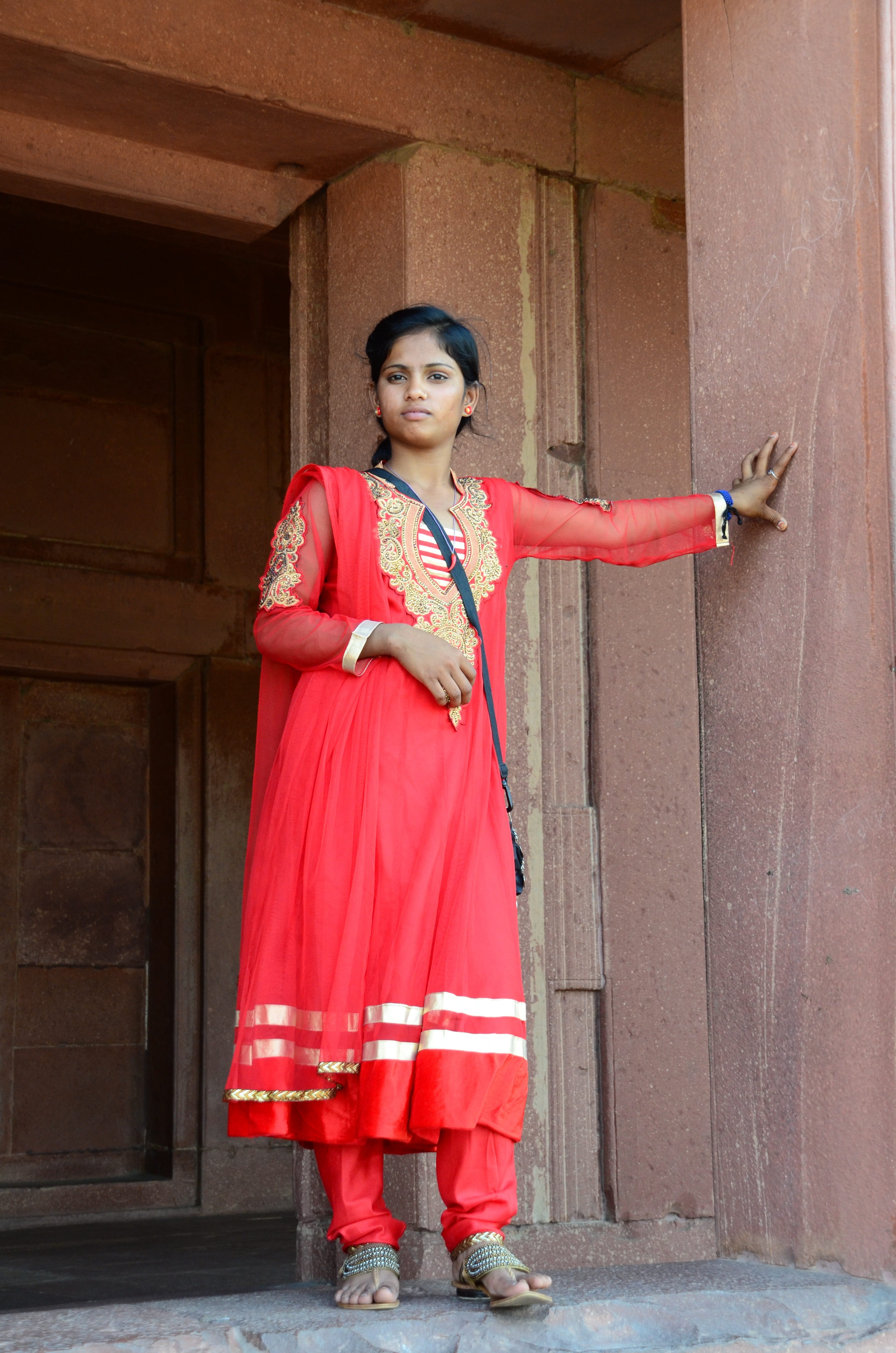 real people, concrete, brown, building, outdoors, human arm, red, fashion, looking at camera, woman, smiling, traditional young, front view, one woman only, Phone HD Wallpaper